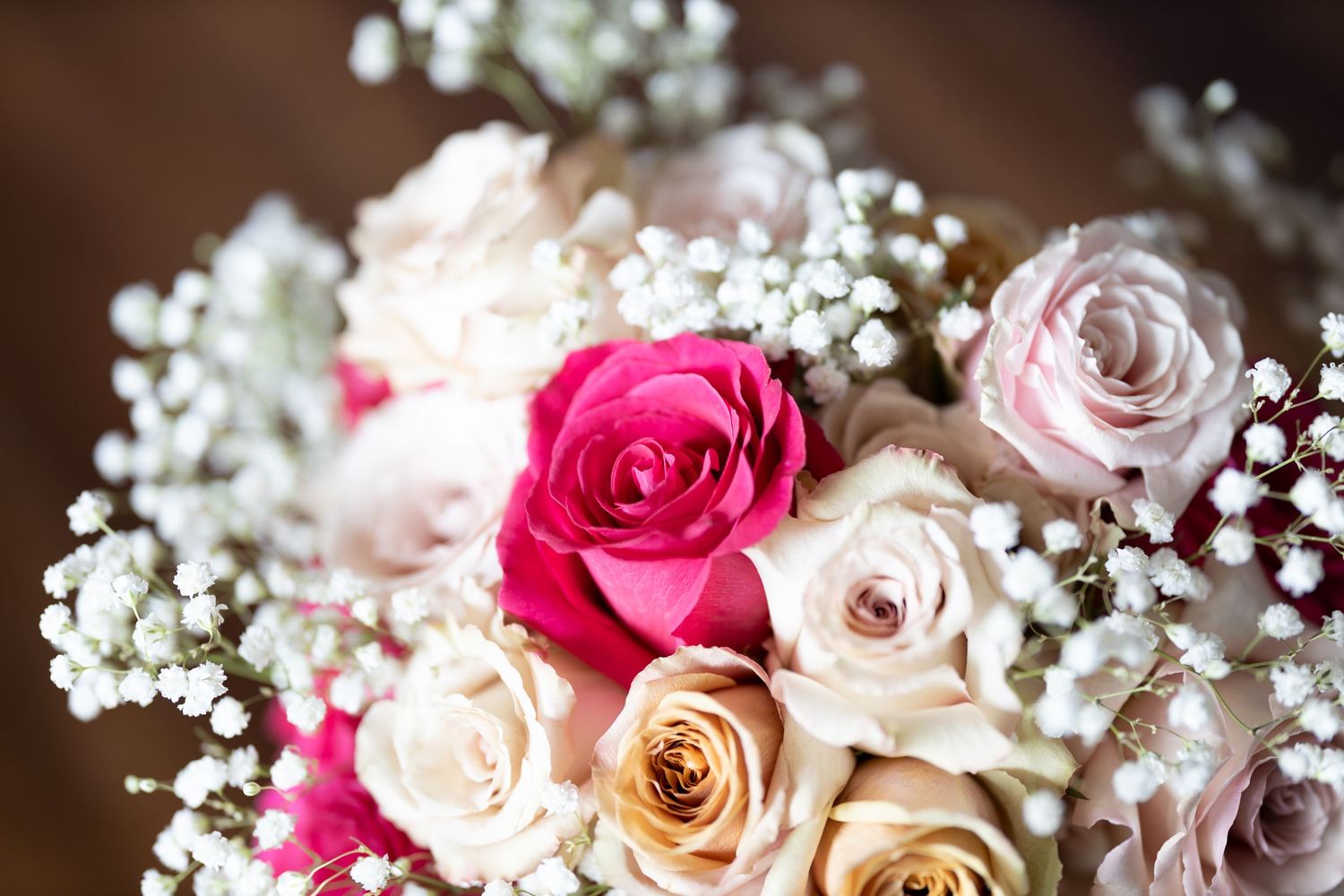 Romantic wedding floral arrangement with mixed pink and cream roses and gypsophila, showcasing a classic elegant wedding color palette.