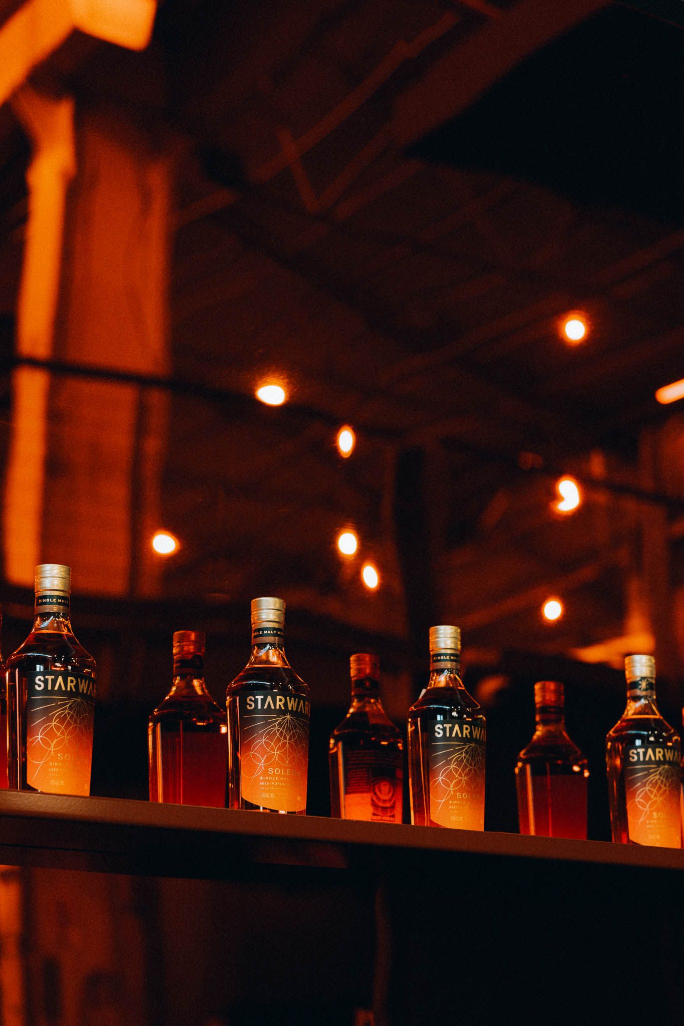 Warm, atmospheric shot of Starward whisky bottles at a bar, perfect for a rustic wedding or bucks party.