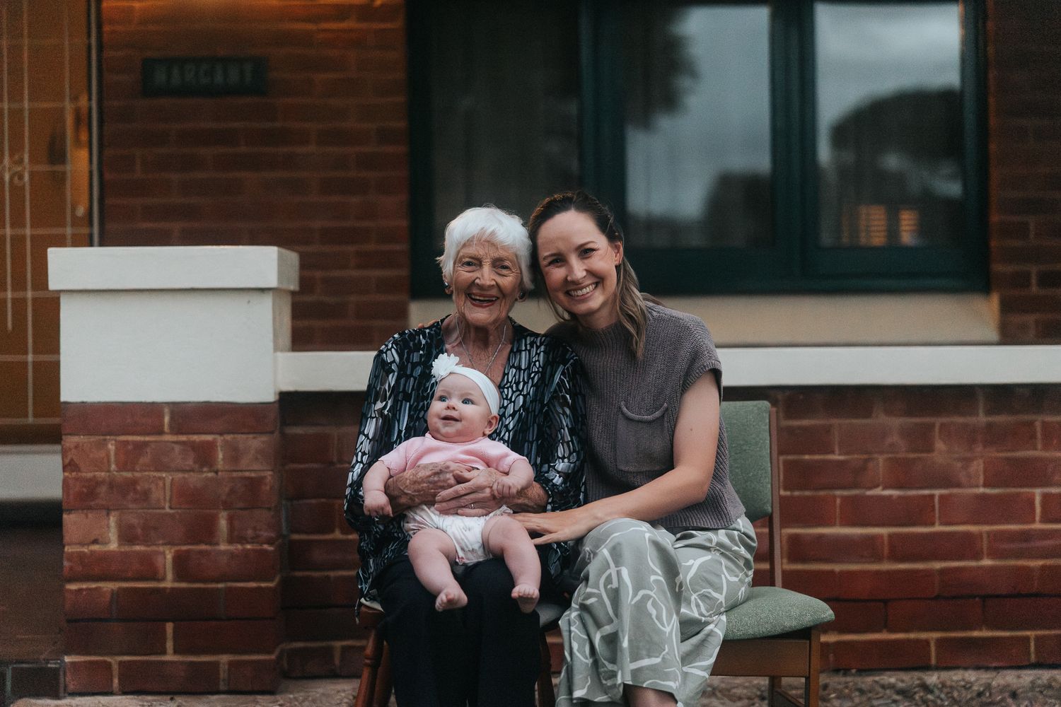 Multi-generational family portrait featuring a great-great-grandmother, mother, and baby girl on a porch in Adelaide.