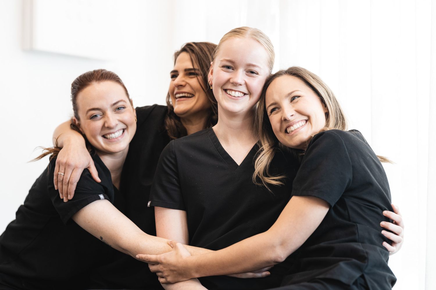 Professional branding photography of four smiling women in black uniforms, ideal for small business team headshots.