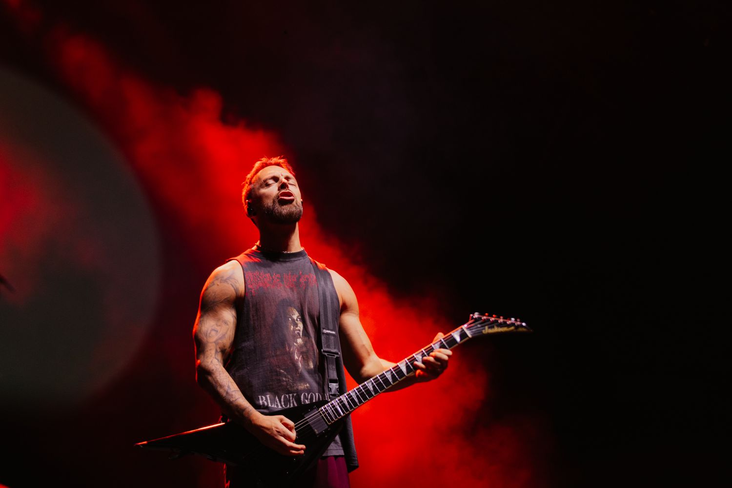 Matt Tuck playing a Jackson V guitar under red stage lights. Sharp live music photography capturing a metal performance in Melbourne.