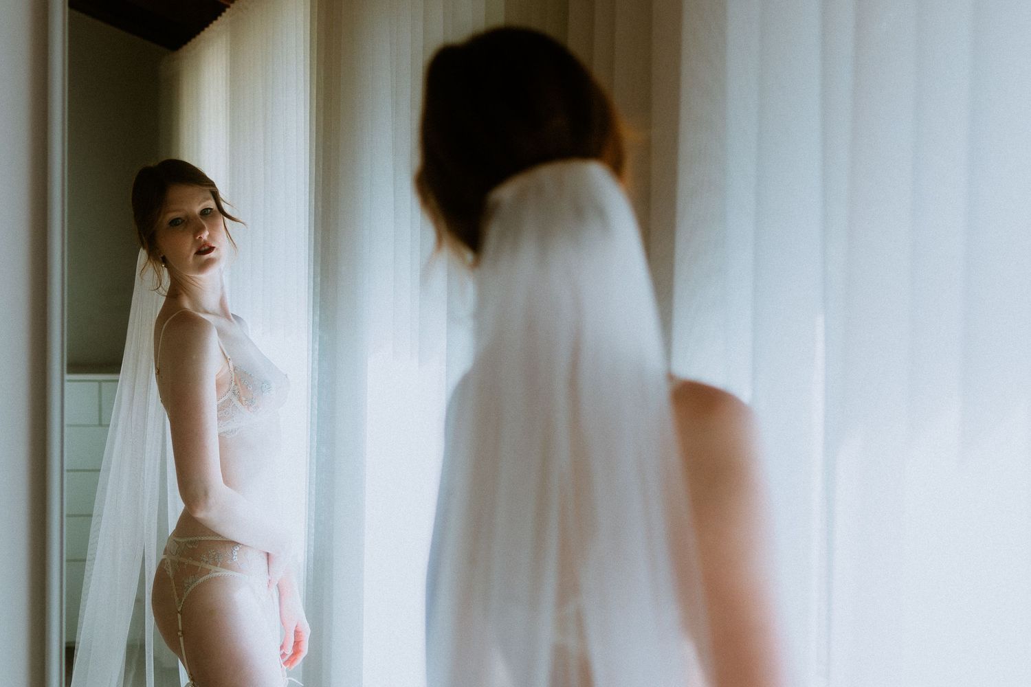 Elegant Melbourne bride wearing a wedding veil and lace lingerie reflecting in a mirror.