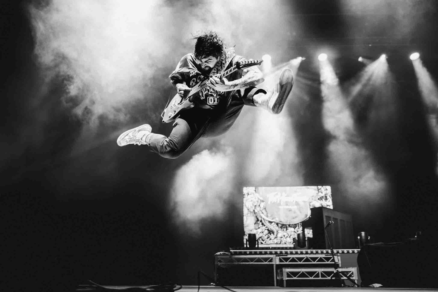 Mid-air action shot of a guitarist jumping during a live performance in Melbourne, professional concert photography. The Home Team