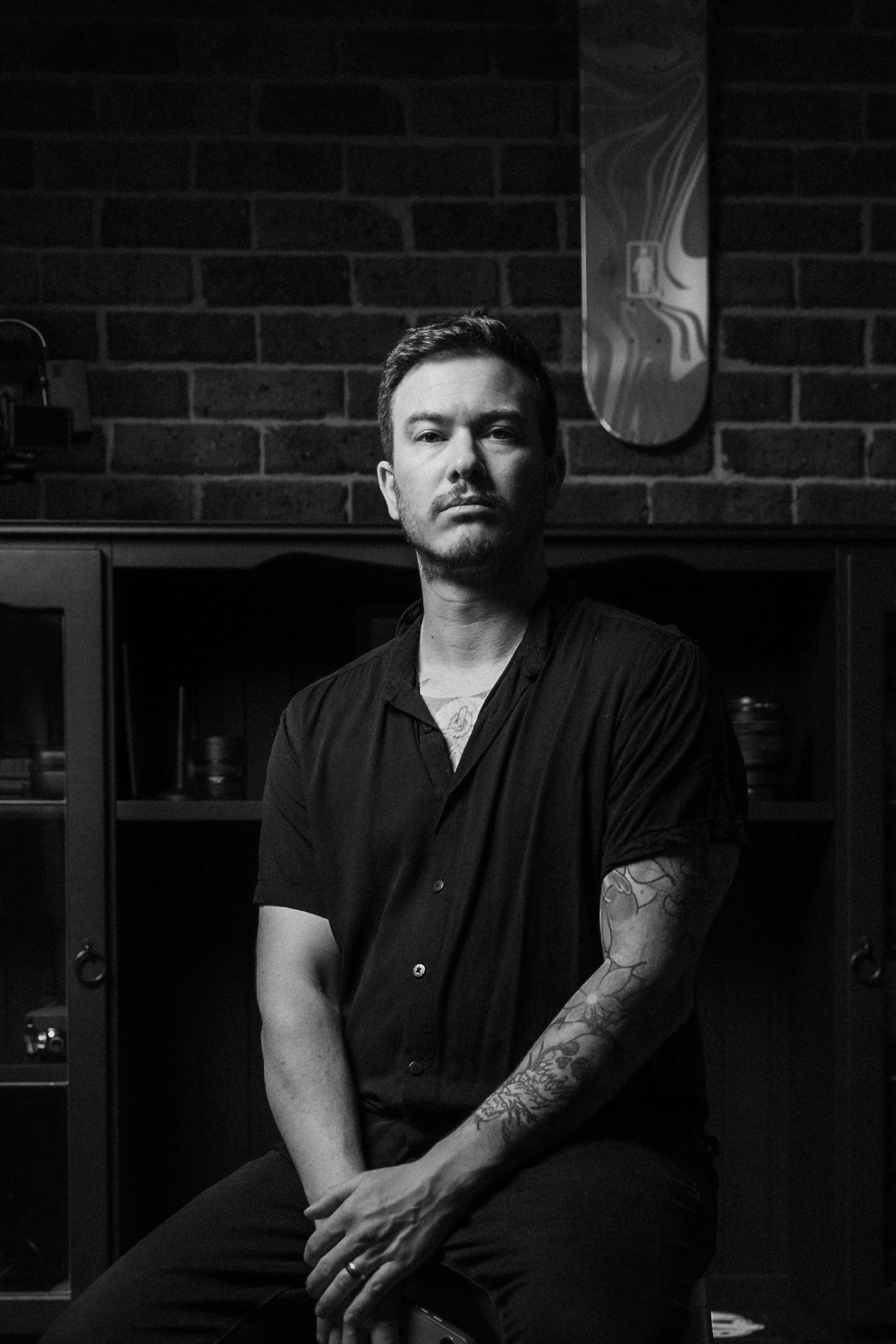 Professional Melbourne wedding photographer portrait in a moody, industrial-style studio with brick background.