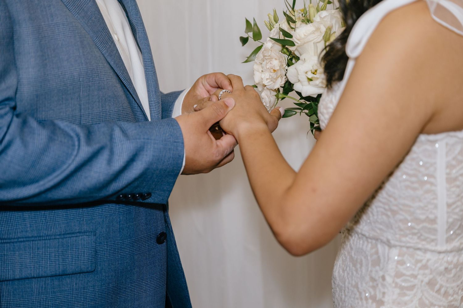 Groom placing a wedding ring on the bride's finger during an intimate ring exchange ceremony.