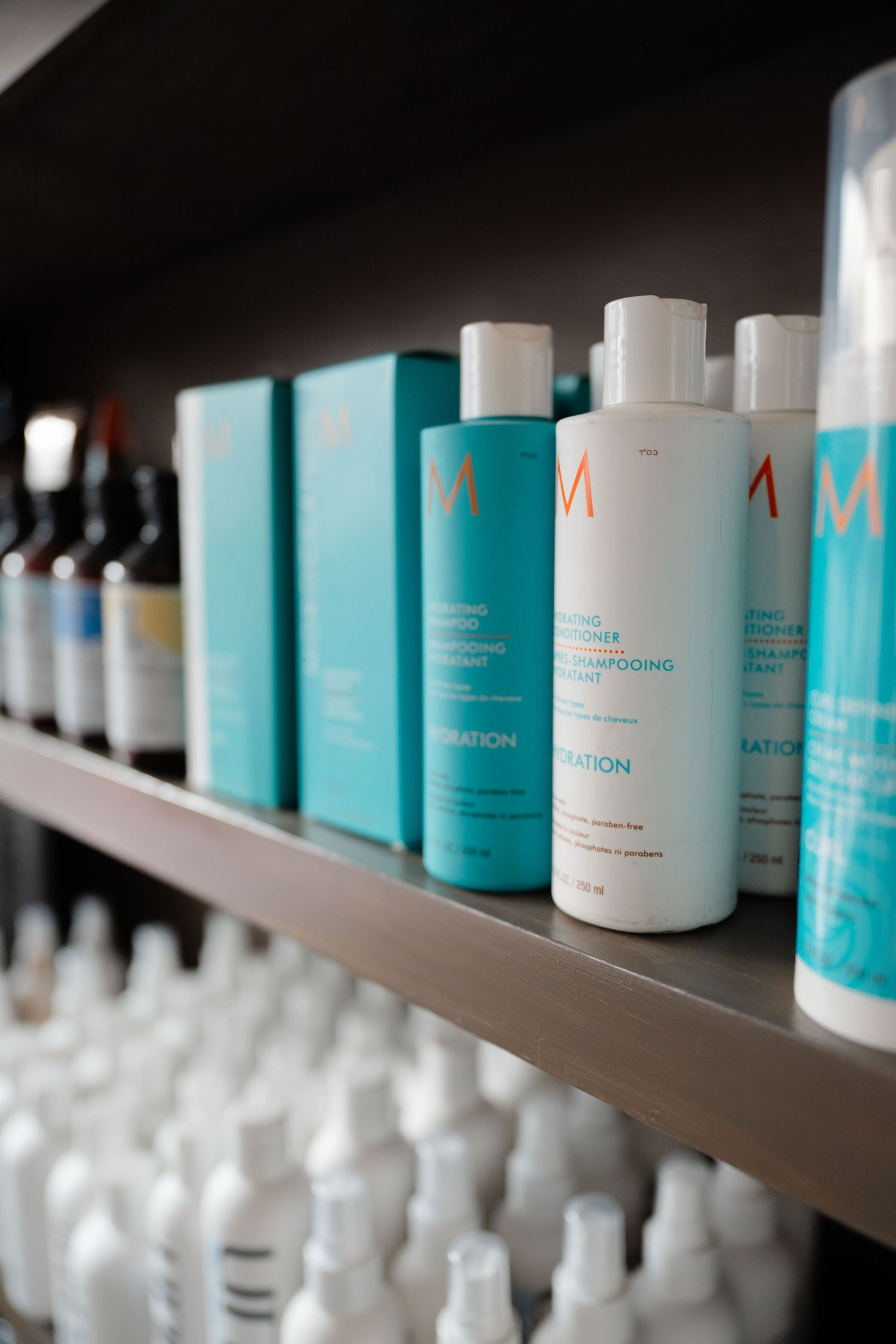 Moroccanoil hydration shampoo and conditioner products displayed on a dark retail shelf in a hair salon.