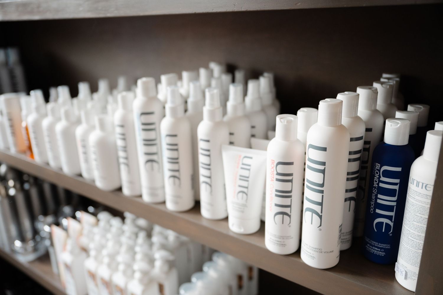 Shelves lined with Unite brand professional hair care products in white bottles at a salon.
