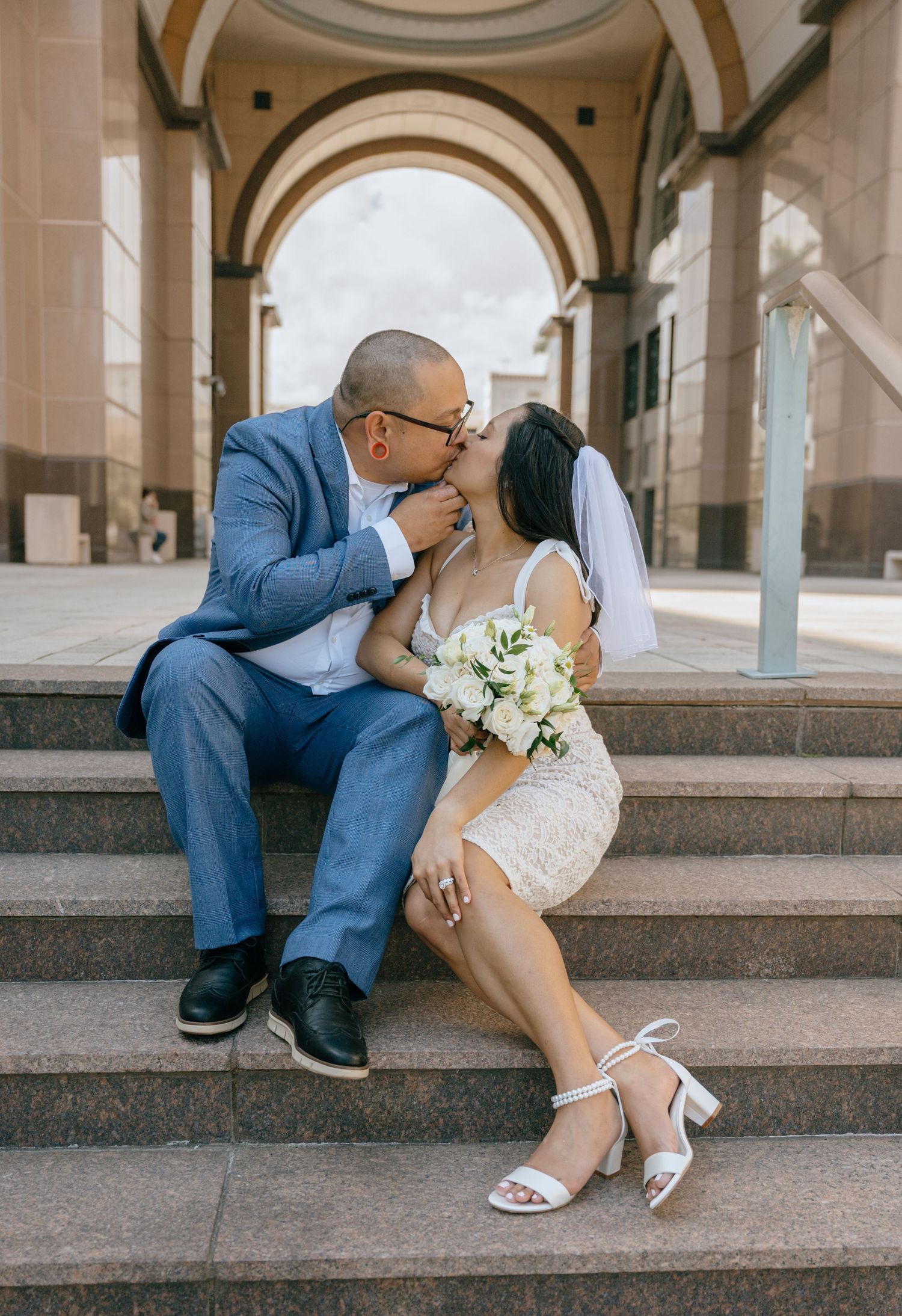 Bride and groom sharing a romantic kiss on courthouse steps after their elopement ceremony.