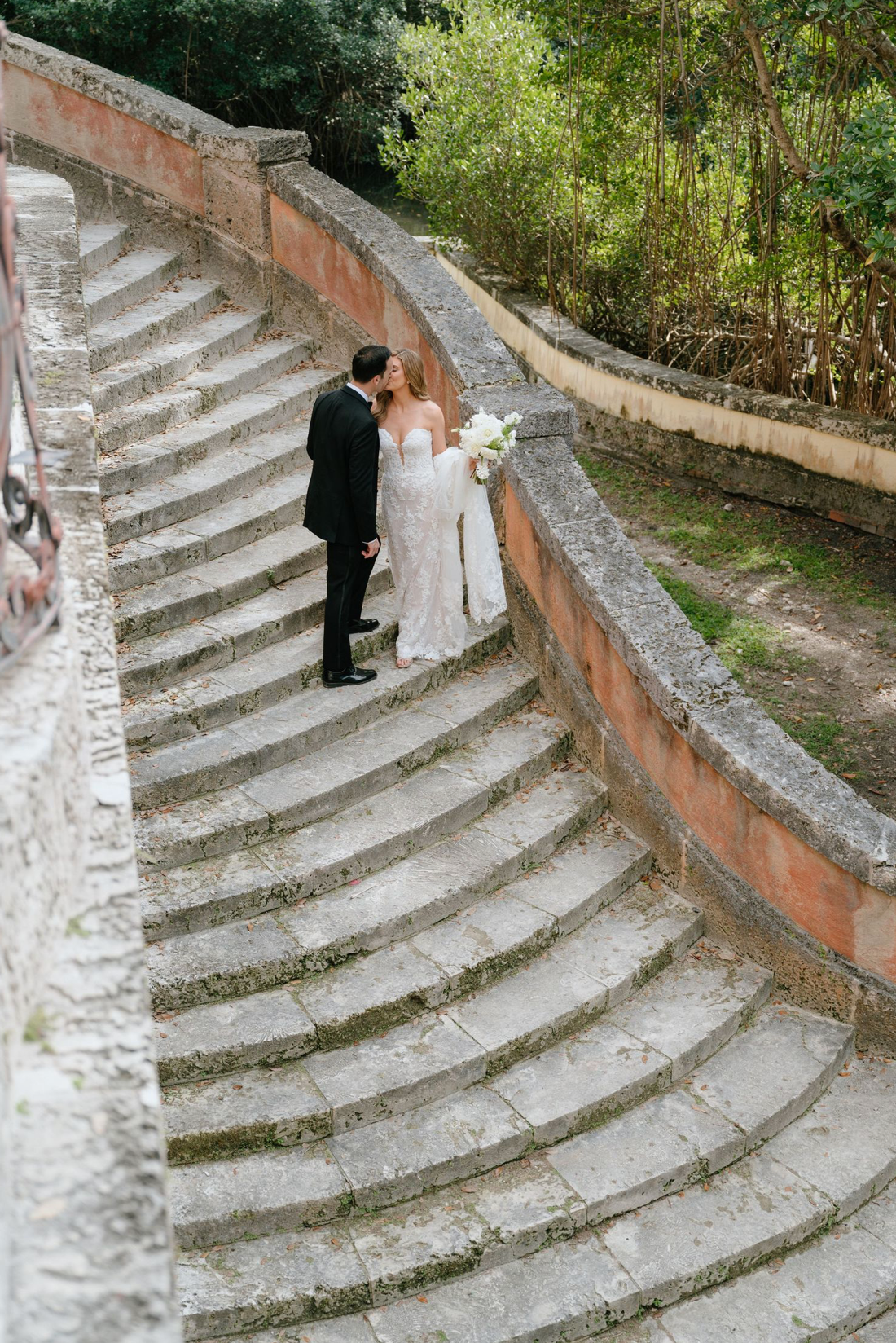 Bride and groom sharing an intimate moment on sweeping curved stone steps at an elegant outdoor wedding venue.