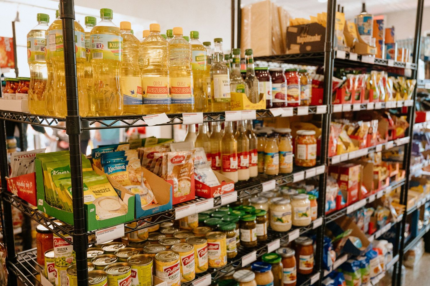Well-stocked grocery store shelves filled with oils, sauces, canned goods, and pantry essentials.