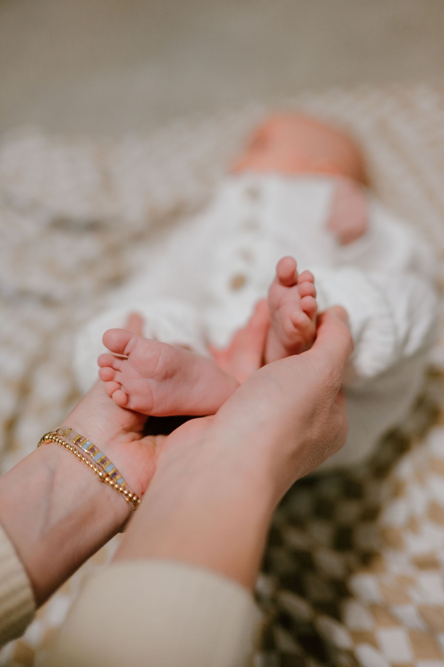 Close-up of a mother's hands gently holding her newborn baby's tiny feet.
