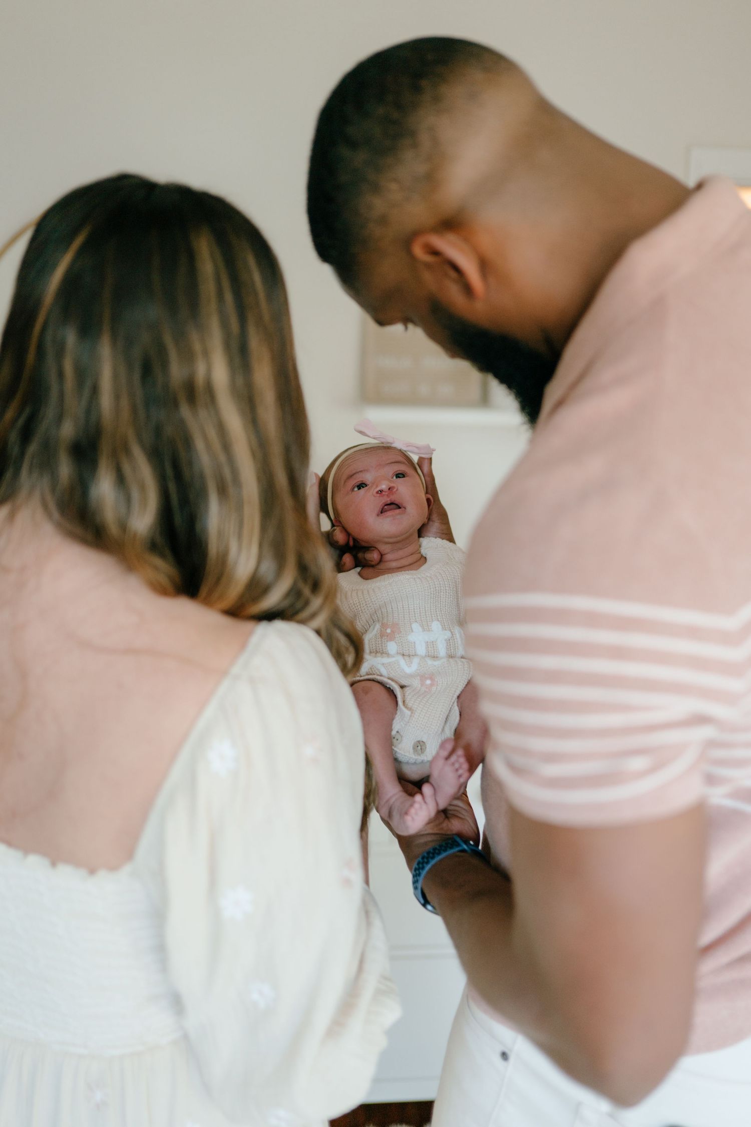 Parents lovingly gazing at their newborn baby girl in a bright nursery.