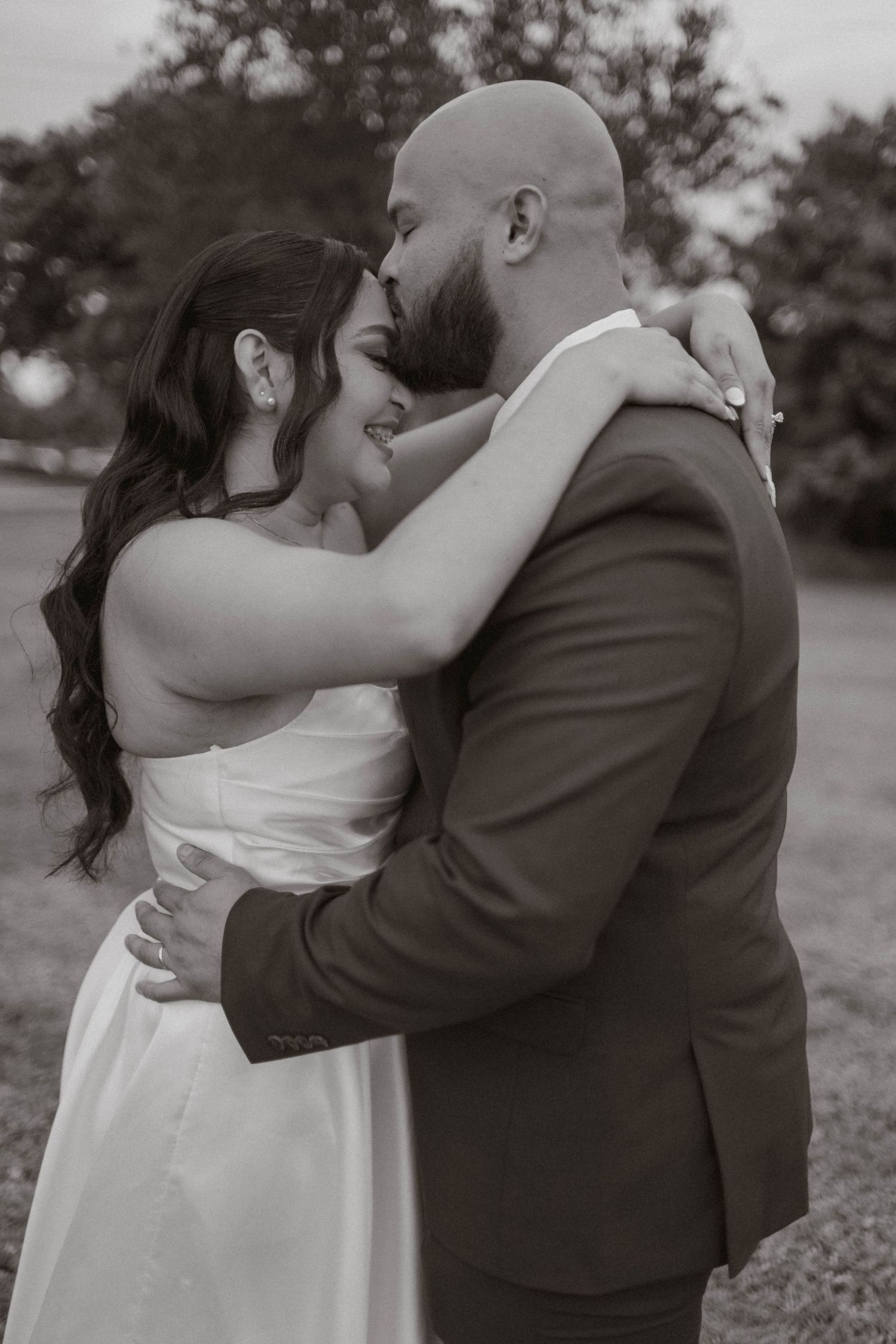 Black and white romantic portrait of newlyweds embracing closely outdoors on their wedding day.