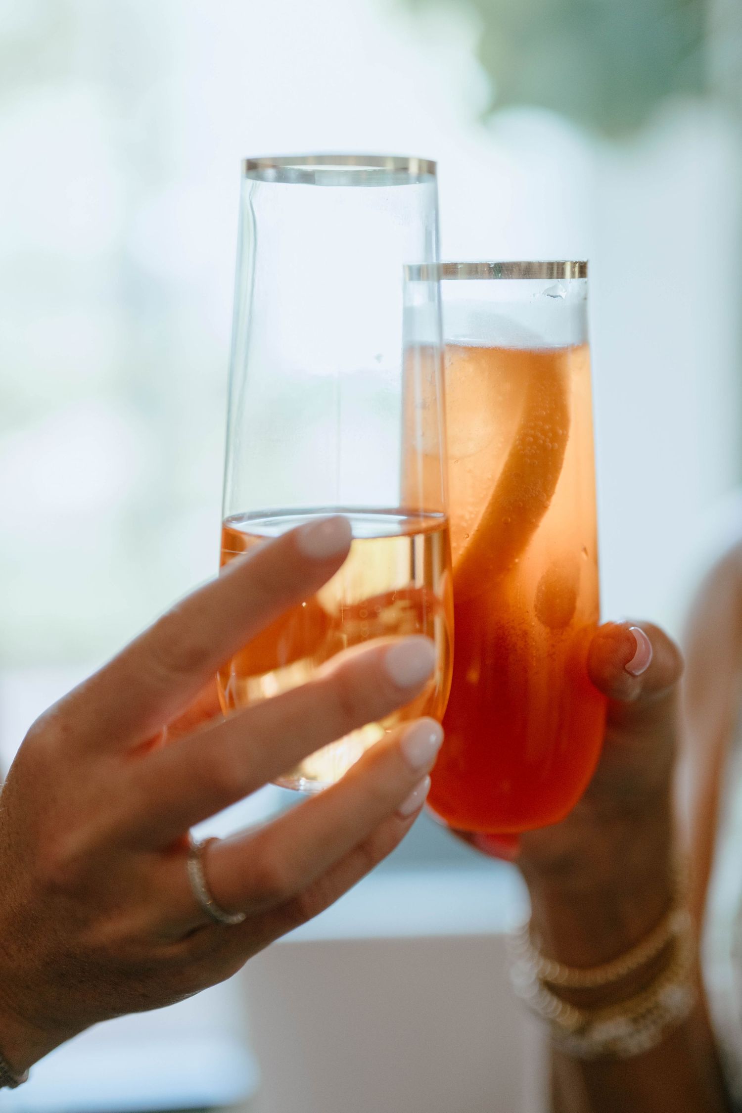 Two people clinking glasses of pink spritz cocktails at a celebration event.
