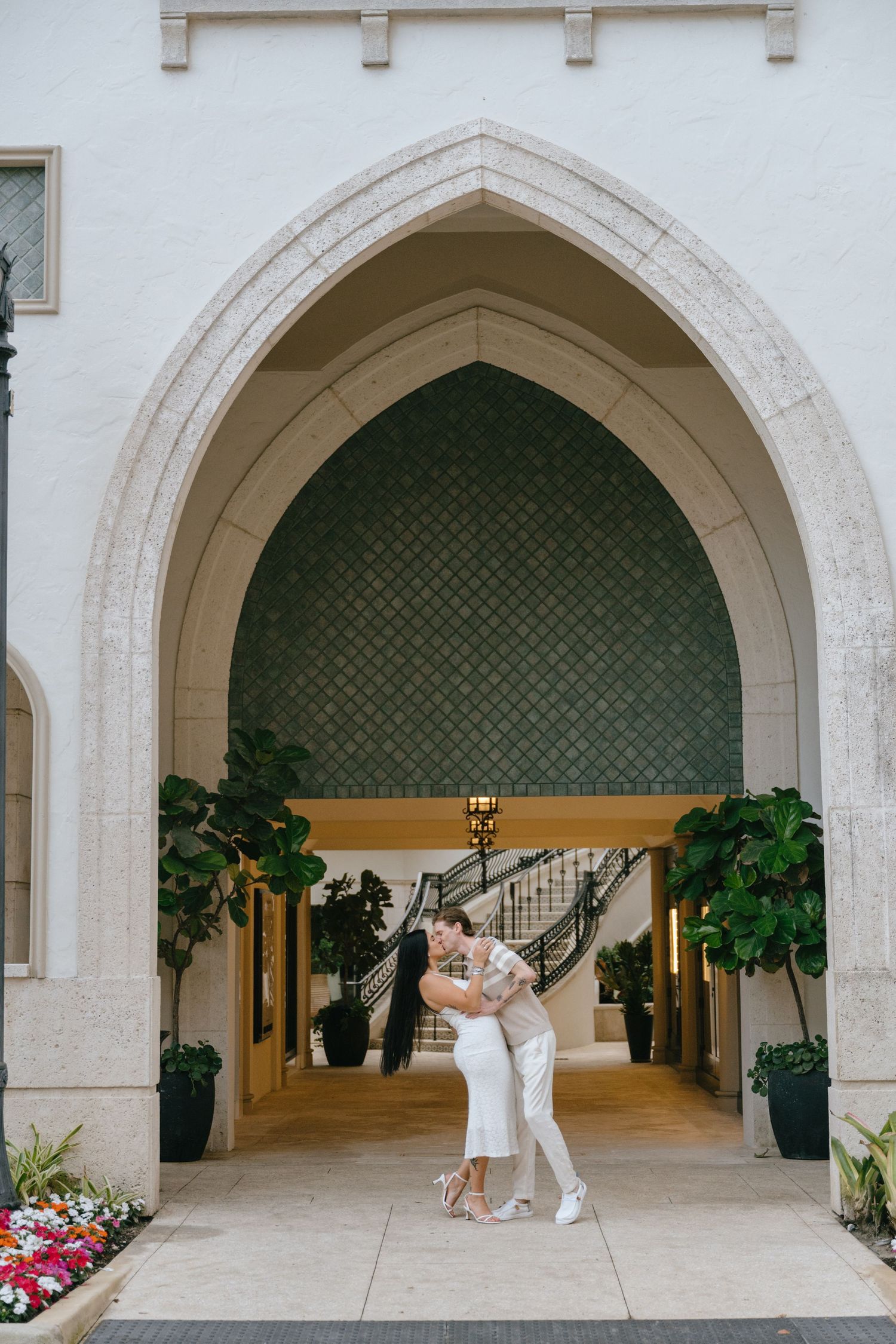 Couple sharing a romantic embrace and kiss under a beautiful Gothic stone archway at a luxury Florida venue.