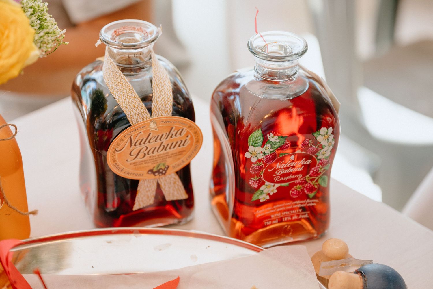 Two decorative glass bottles of Nalewka Babuni Polish fruit liqueur with strawberry and dark berry flavors.