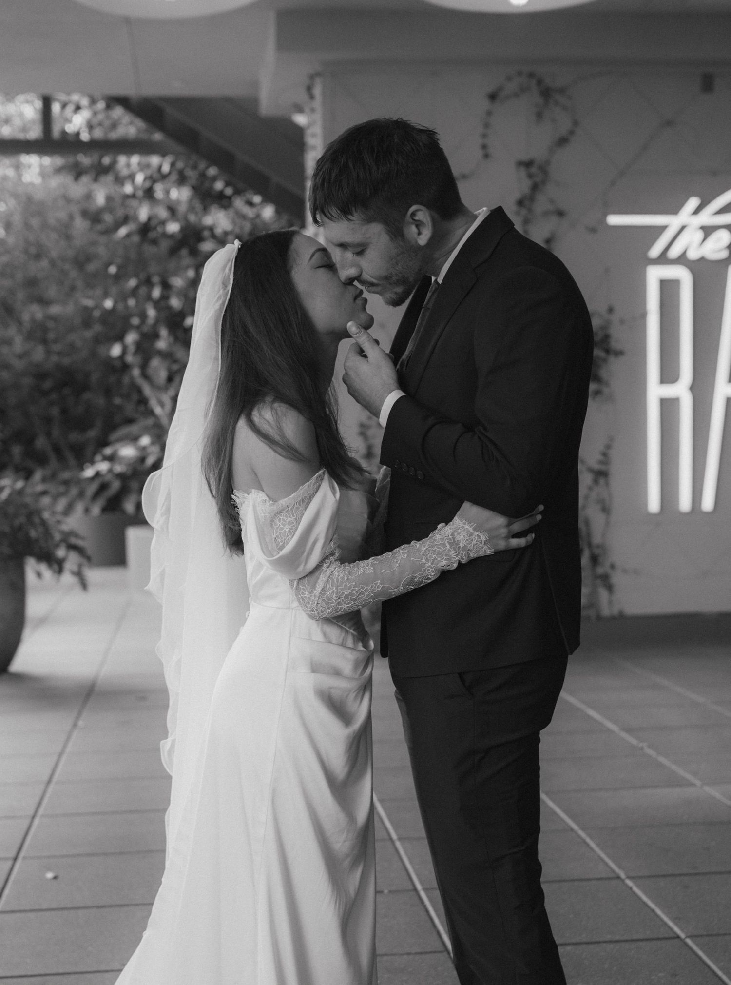 Black and white photo of bride and groom sharing romantic kiss at wedding venue.