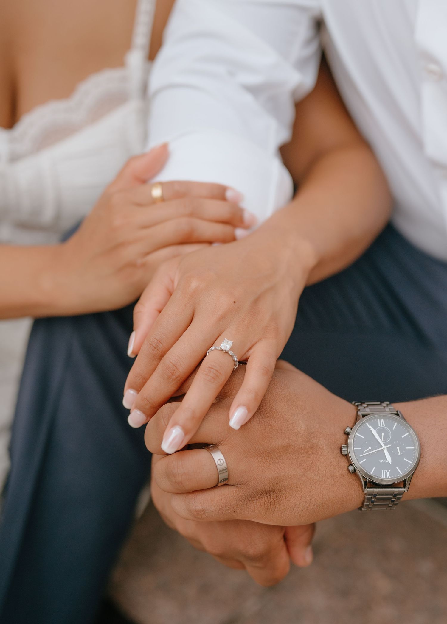 Close-up of newlyweds hands showing engagement ring, wedding band, and a stylish watch.