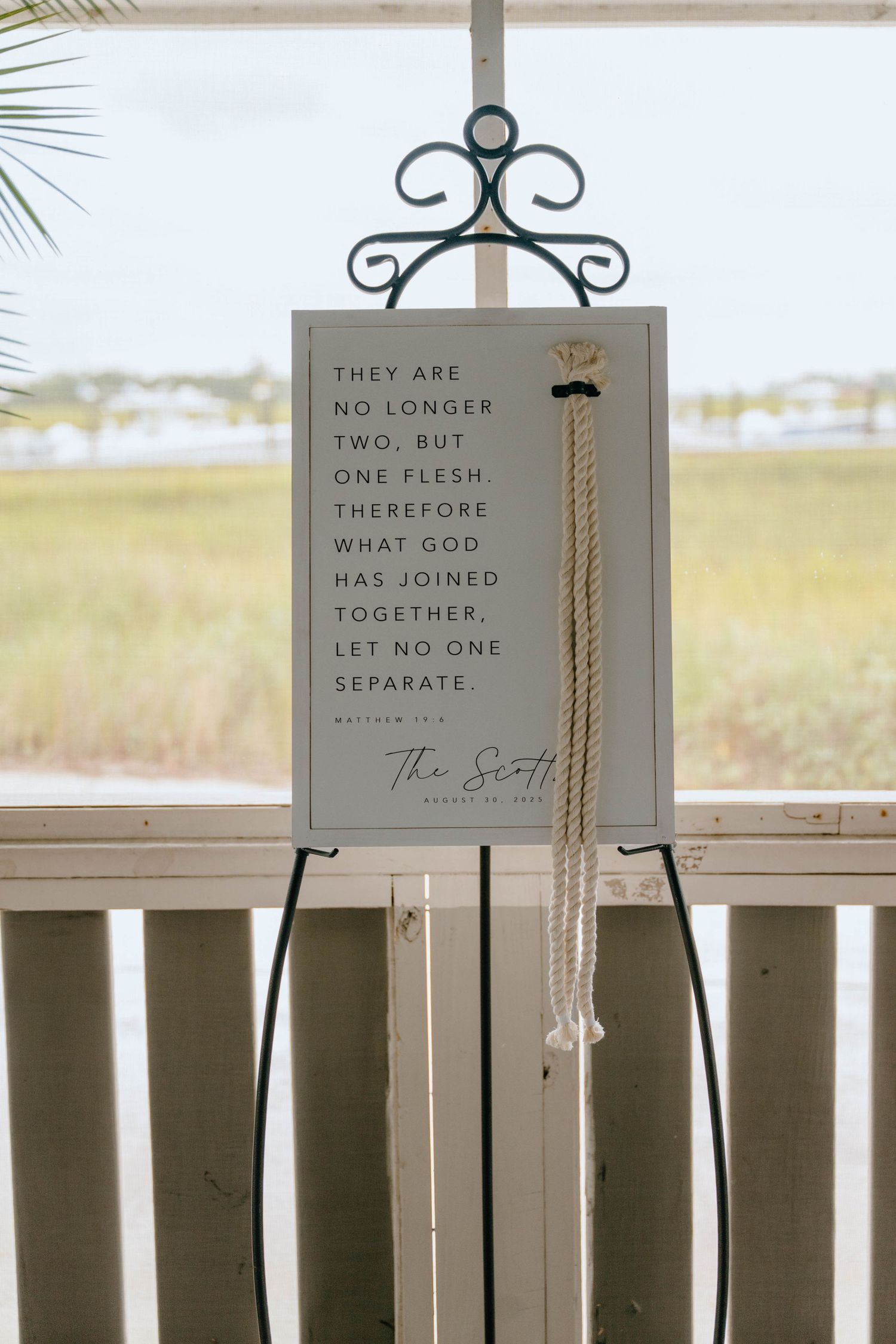 Wedding sign with Matthew 19:6 scripture quote displayed outdoors with rope unity cord.