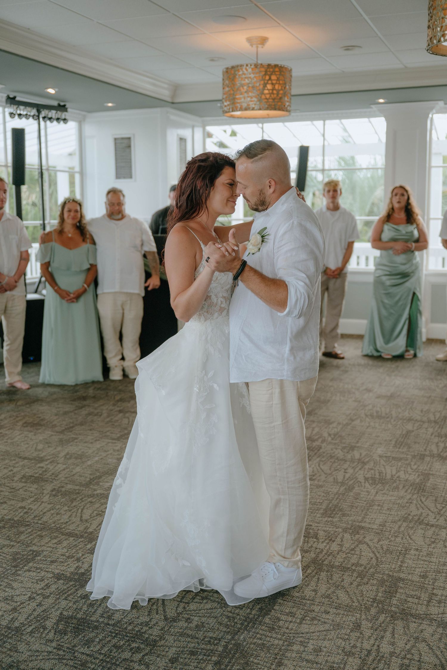 Bride and groom share intimate first dance surrounded by wedding guests in elegant reception venue.