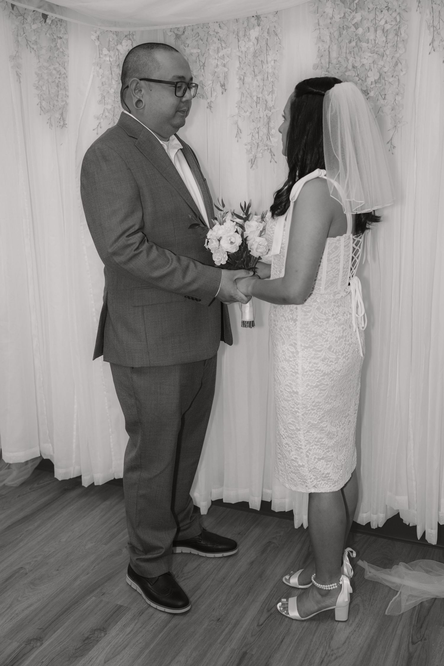 Couple exchanging vows and holding hands in a bridal boutique during an intimate ceremony.