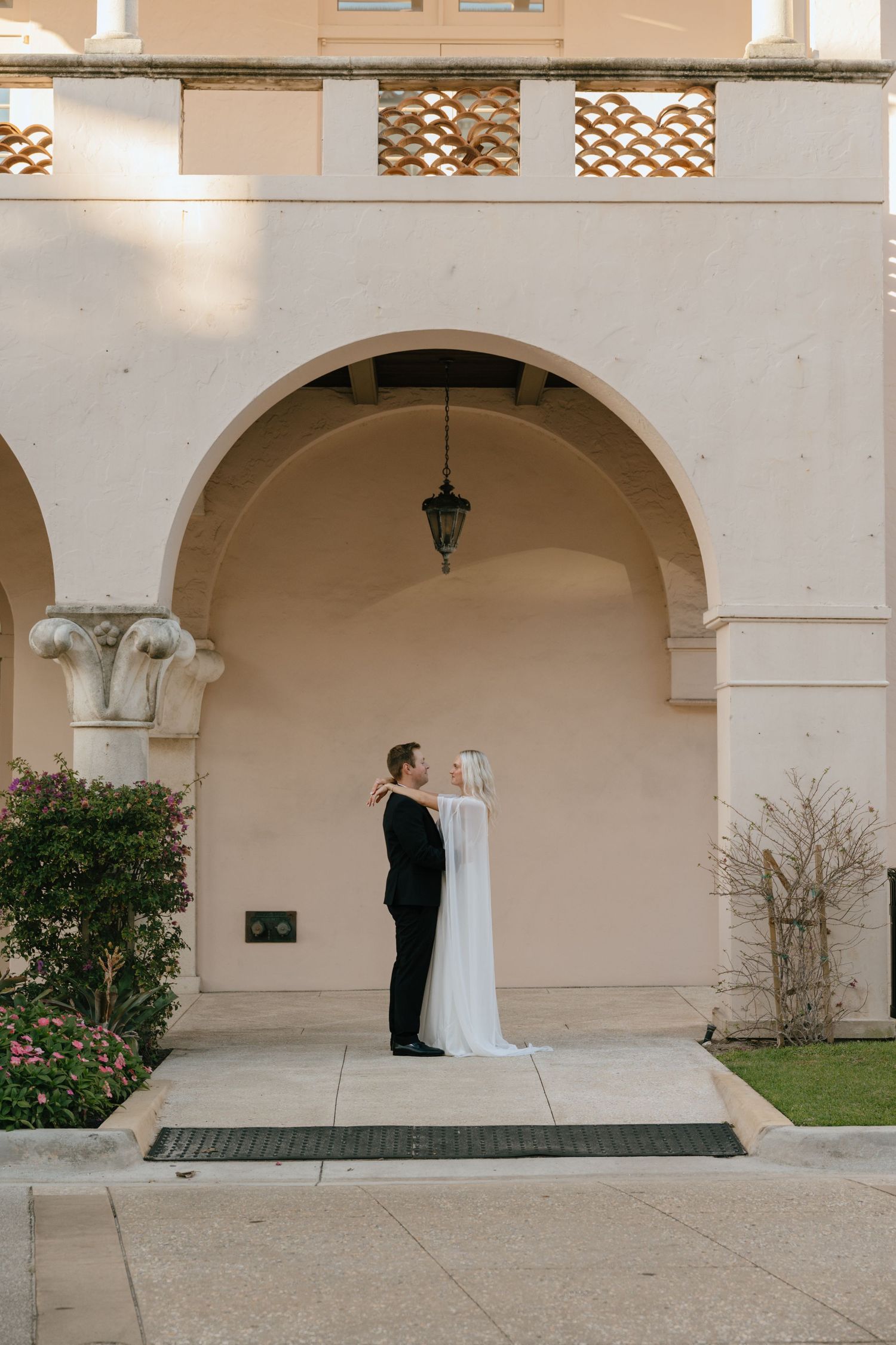 Bride and groom share an intimate moment under a beautiful arched doorway of a historic building.