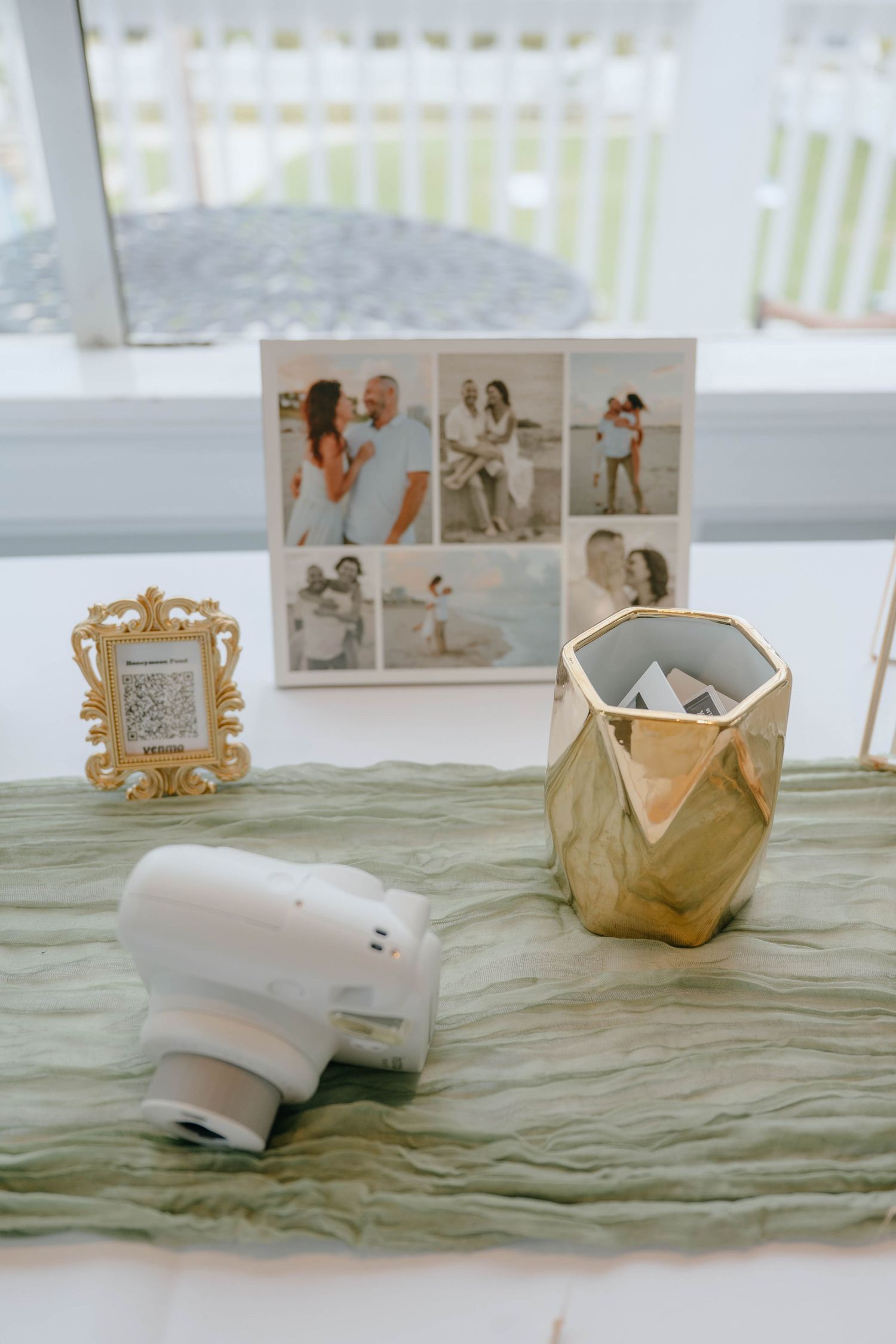 Wedding guest book table with Instax camera, gold geometric vase, and couple photo collage display.