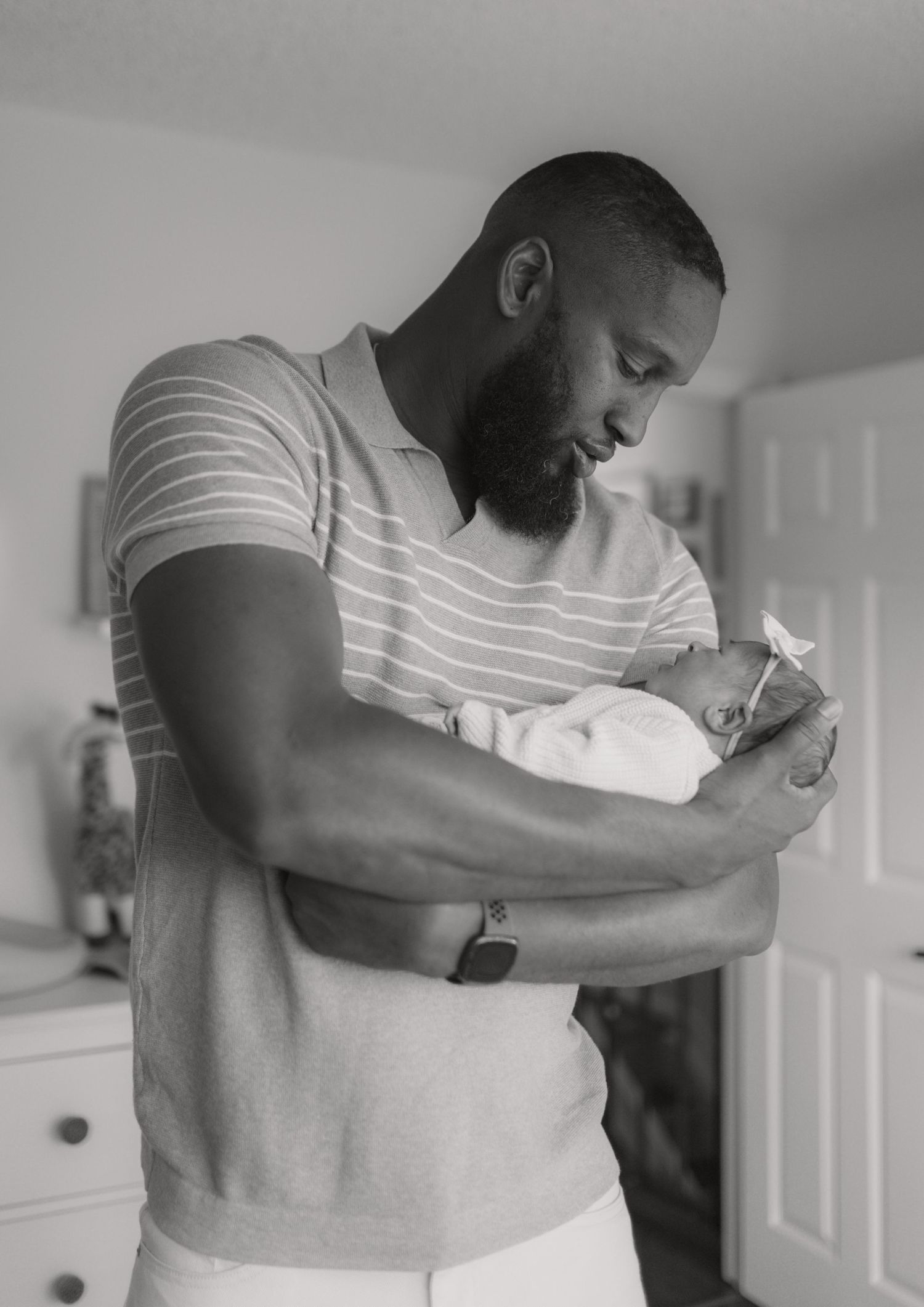Black and white photo of a father tenderly cradling his sleeping newborn.