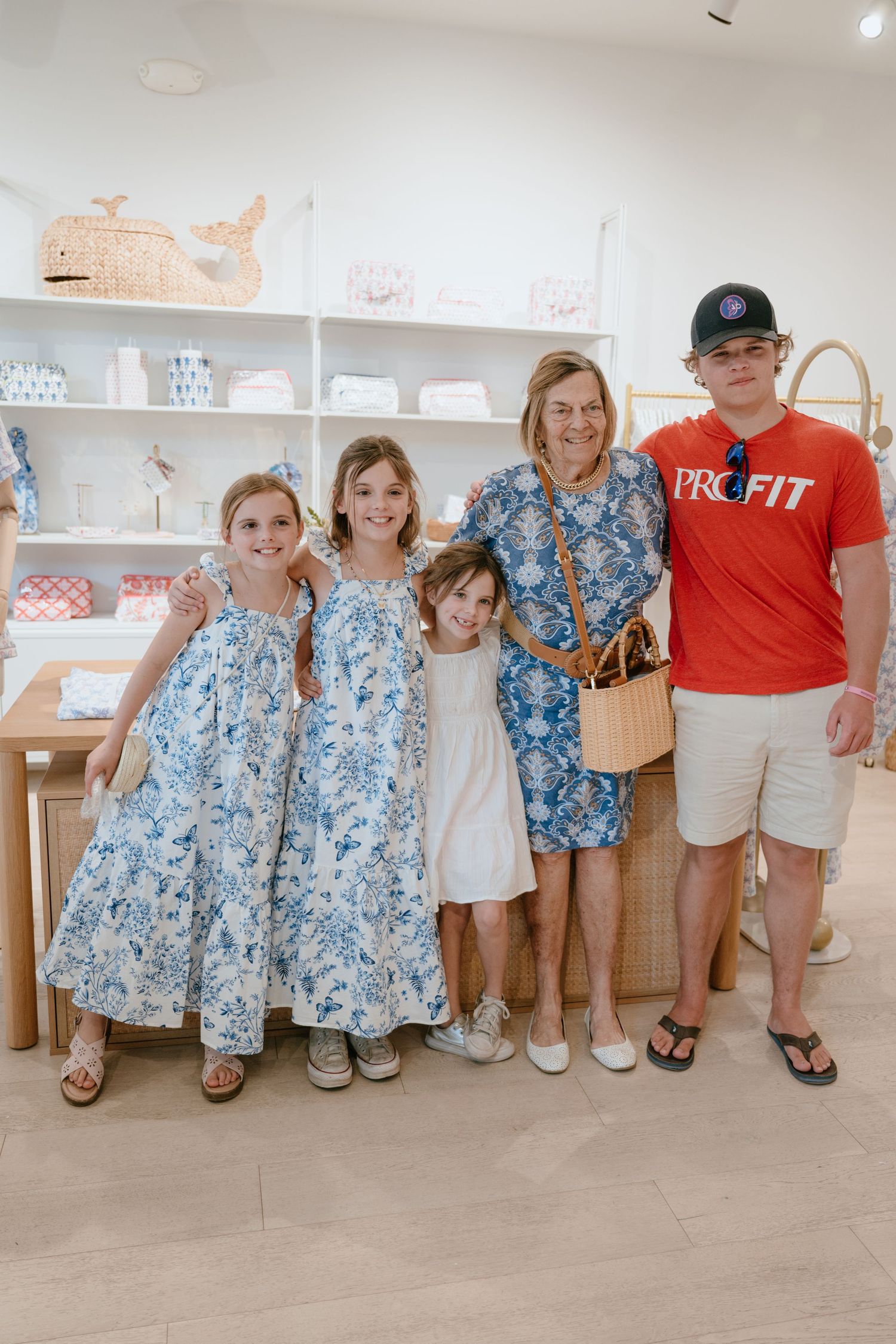 Family of five posing together in Roller Rabbit boutique store with blue and white decor.