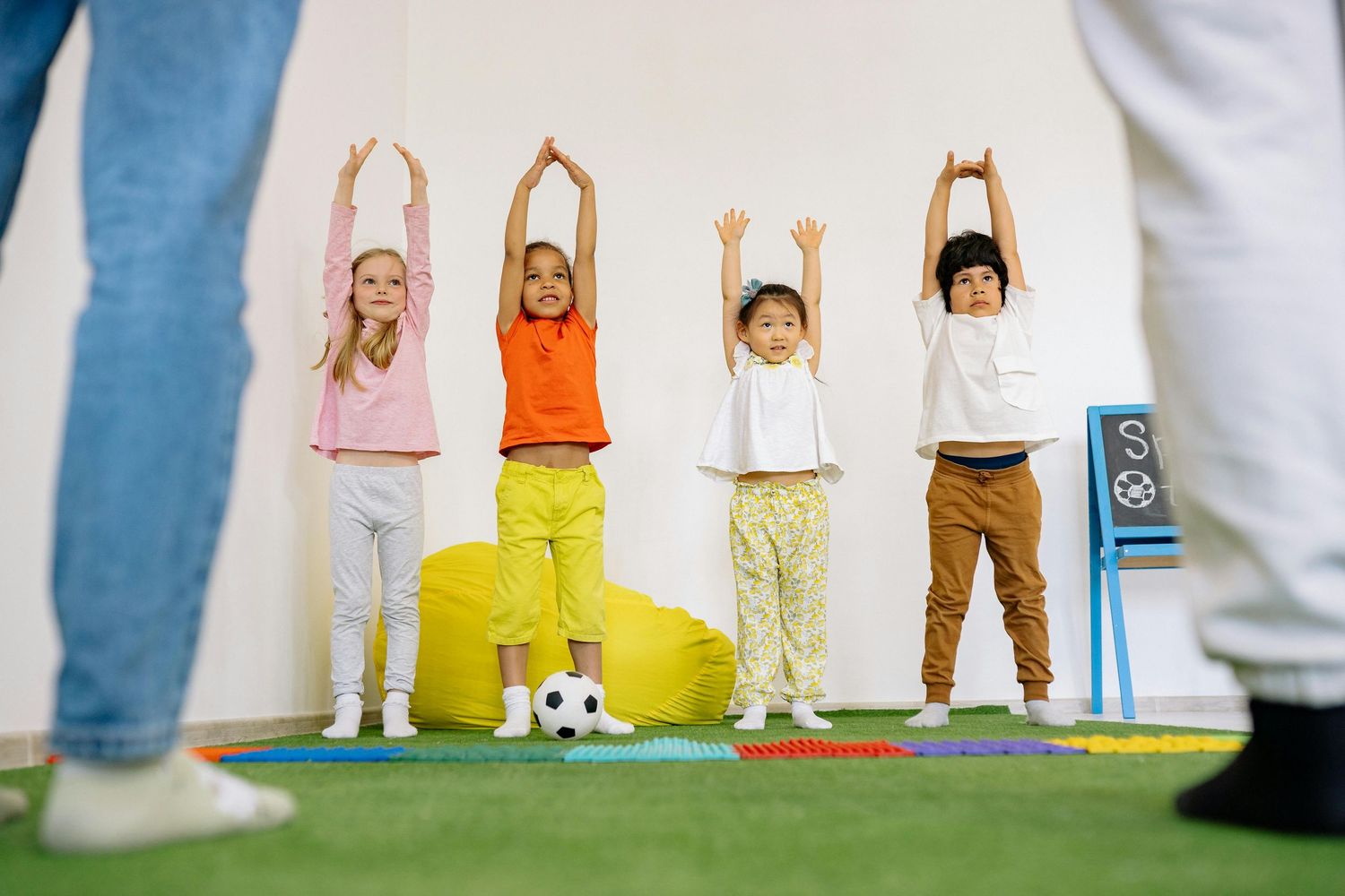 Queen Creek  Arizona Daycare Photography Children lined up against a white wall wearing colorful casual clothing during a group activity.