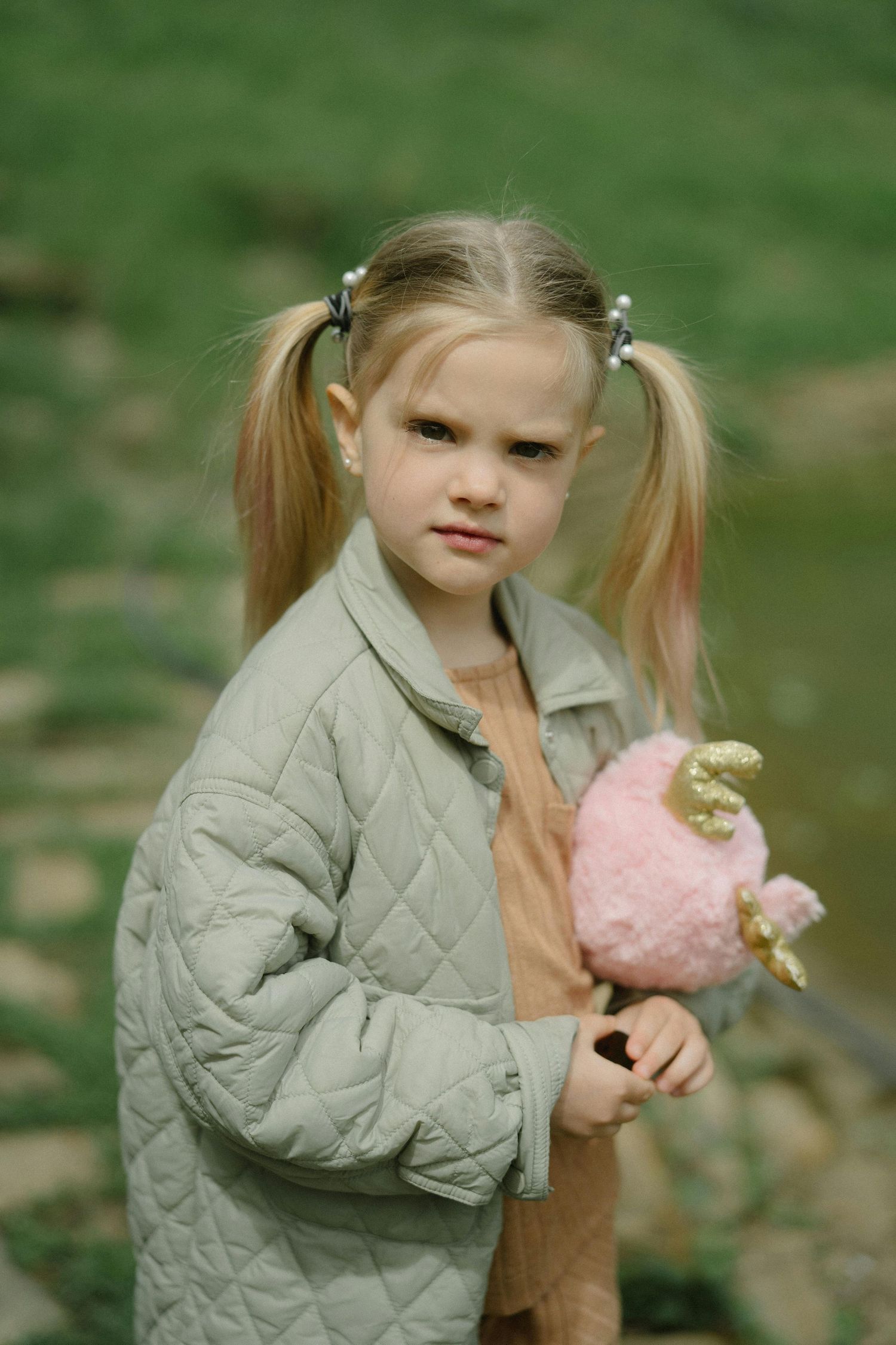 Kingman Arizona Family Photography  A child in a gray quilted jacket holding a pink toy outdoors.