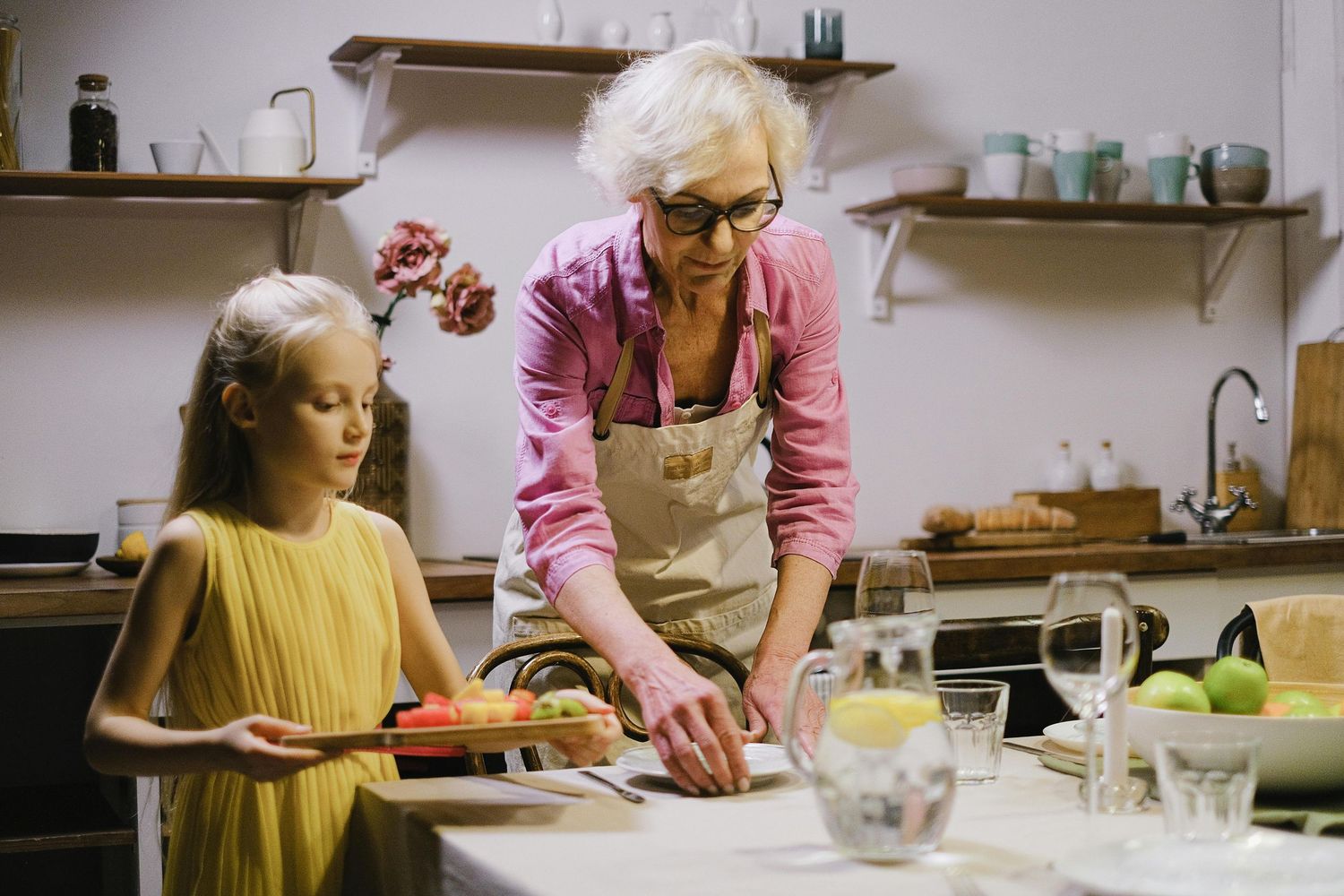 A person in a yellow sweater works at a kitchen counter while someone in pink assists with food preparation. Arcadia Arizona.