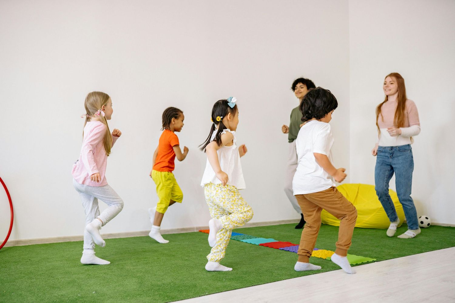 Arizona Daycare Photography Group of children walking in line on artificial grass during an indoor activity.