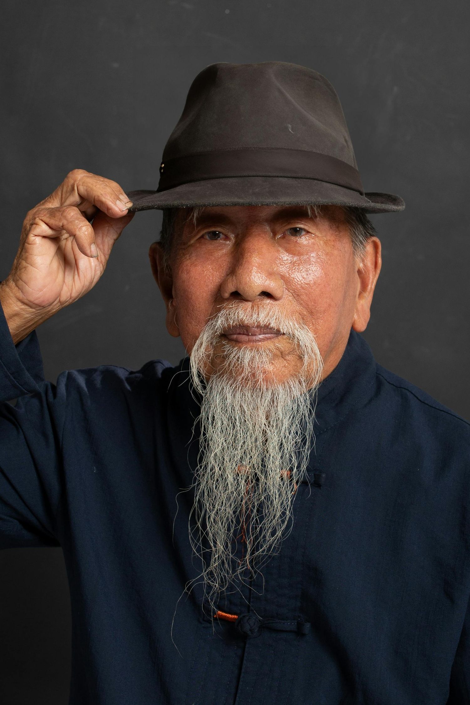 A series of black and white portraits showing an elderly man with a long white beard wearing a dark cap and shirt.