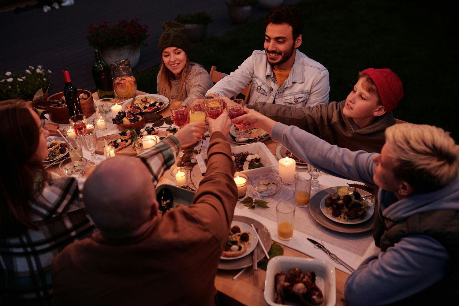 Guests seated at a dimly lit dinner table enjoying conversation and drinks.