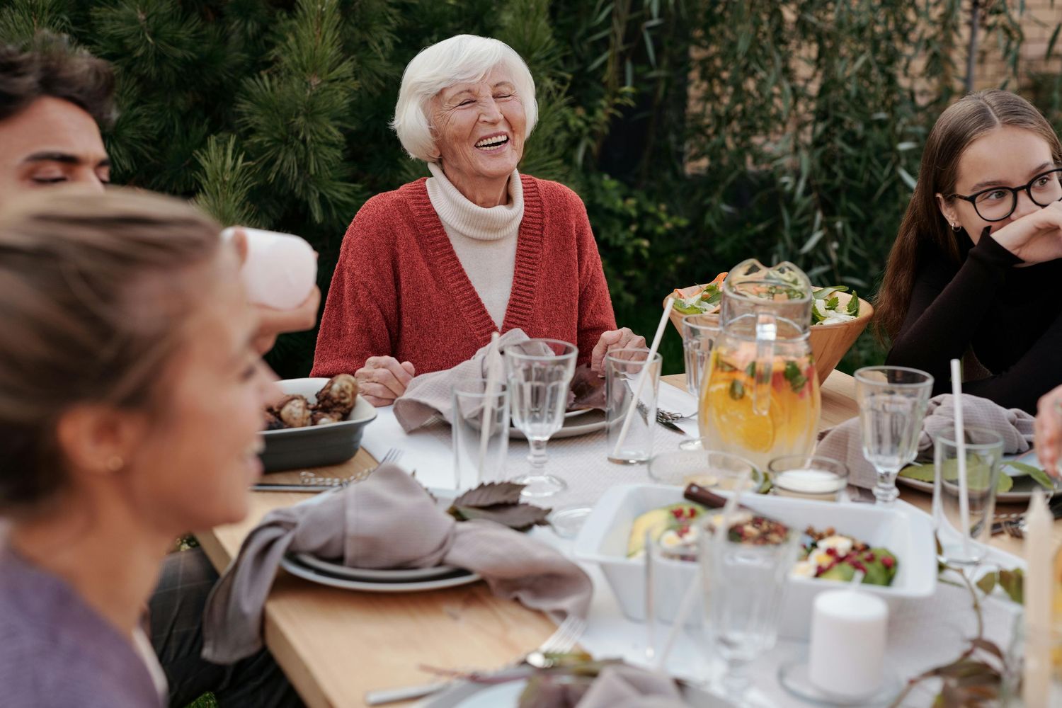 Senior Photography Phoenix. People enjoying a festive outdoor dinner gathering with drinks and food at a wooden table.