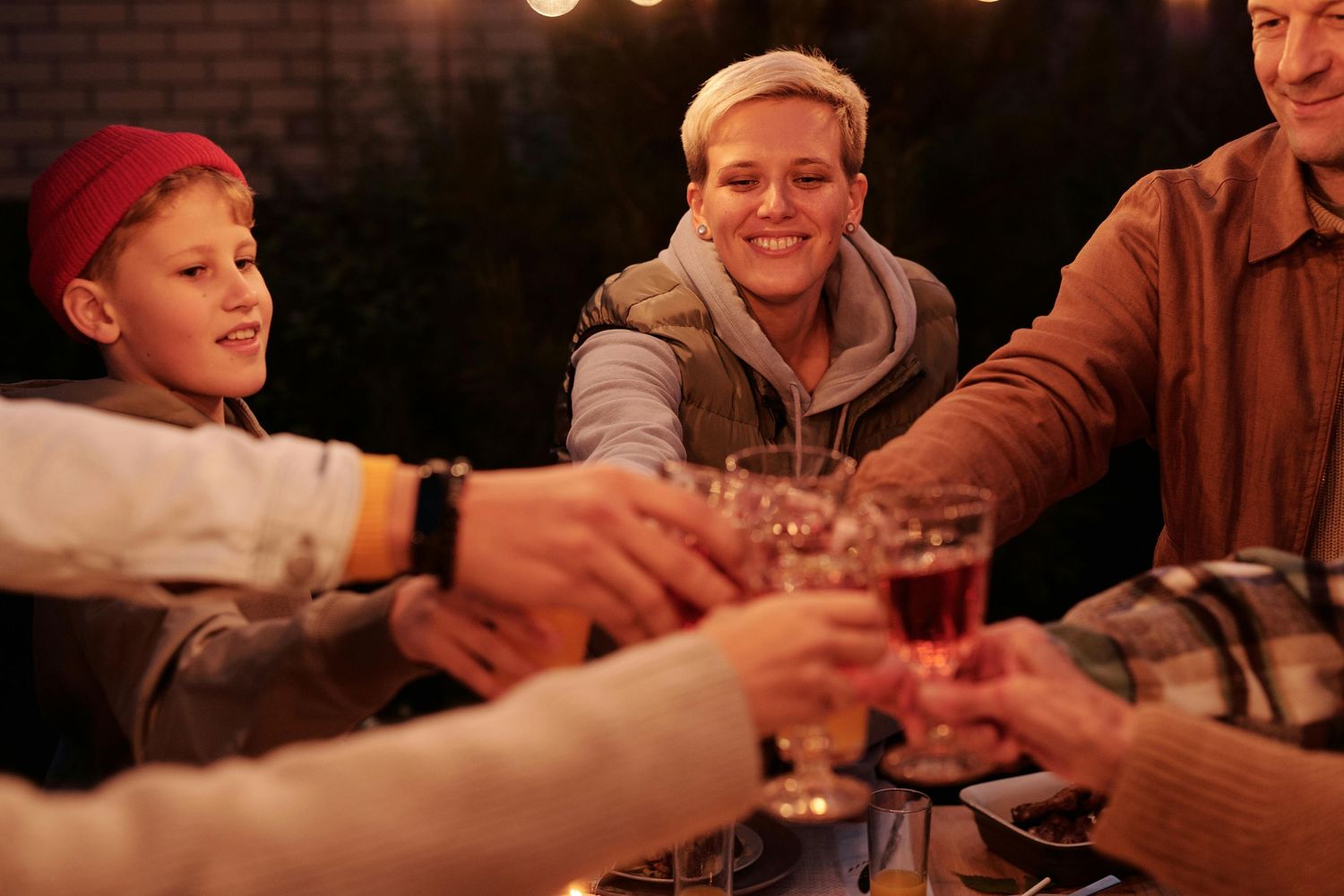 Friends clink glasses together in celebration during a cozy evening gathering at a restaurant.
