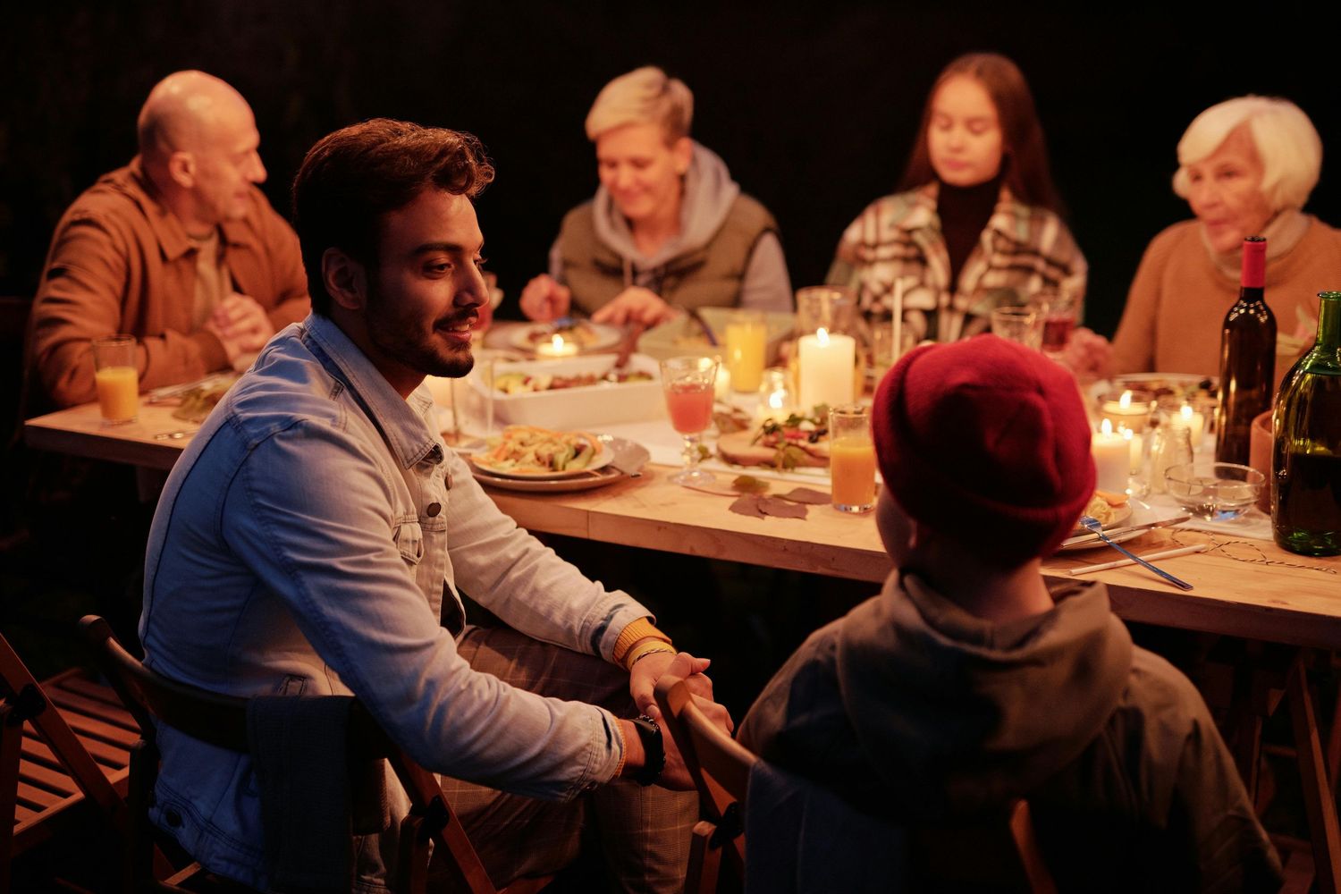Diners gather around candlelit tables in a cozy restaurant setting during evening service.