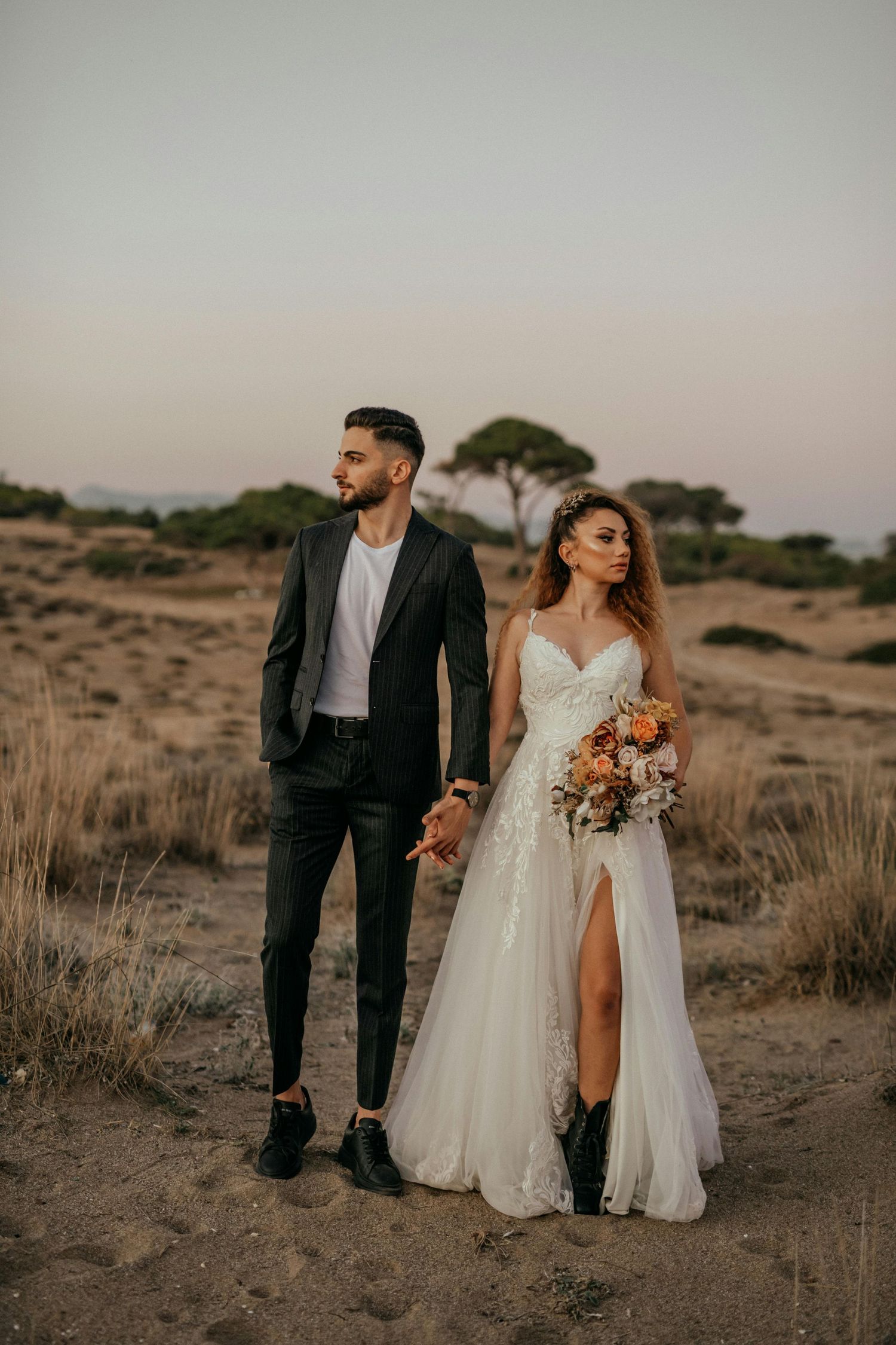 Newlywed couple walking through a rustic desert landscape during their wedding photo session. Trusted Sedona Photographer.