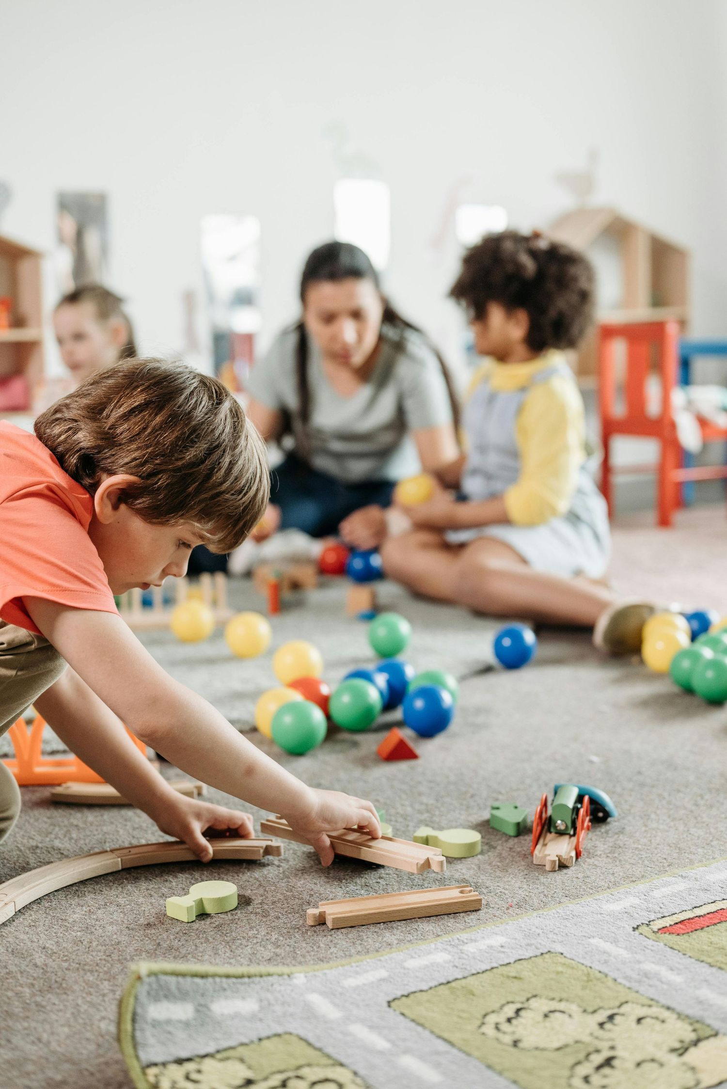Scottsdale Arizona Photography Children engaged in floor activities with colorful balls and wooden tracks.