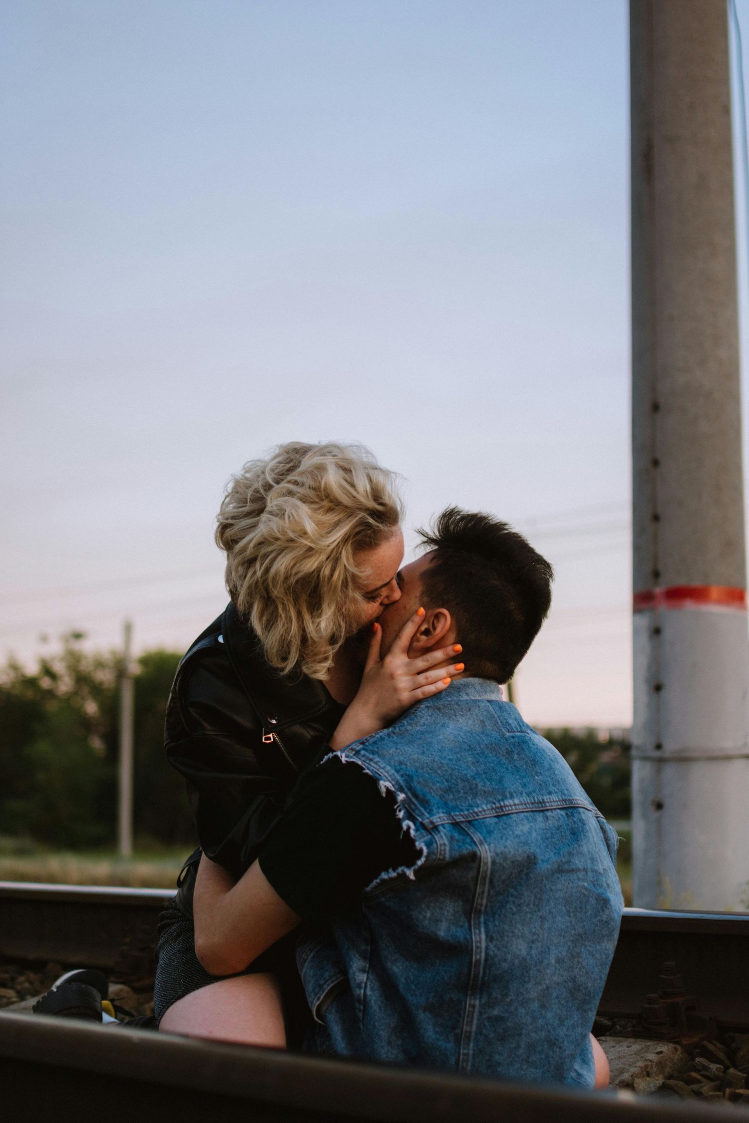 Two people share an intimate moment at sunset while sitting outdoors in a denim jacket and black clothing. Top Photographer Scottsdale.