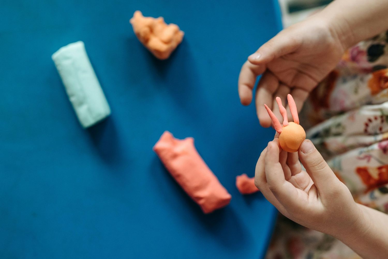 Scottsdale Arizona Photography Hands holding colorful play items against a bright blue surface.