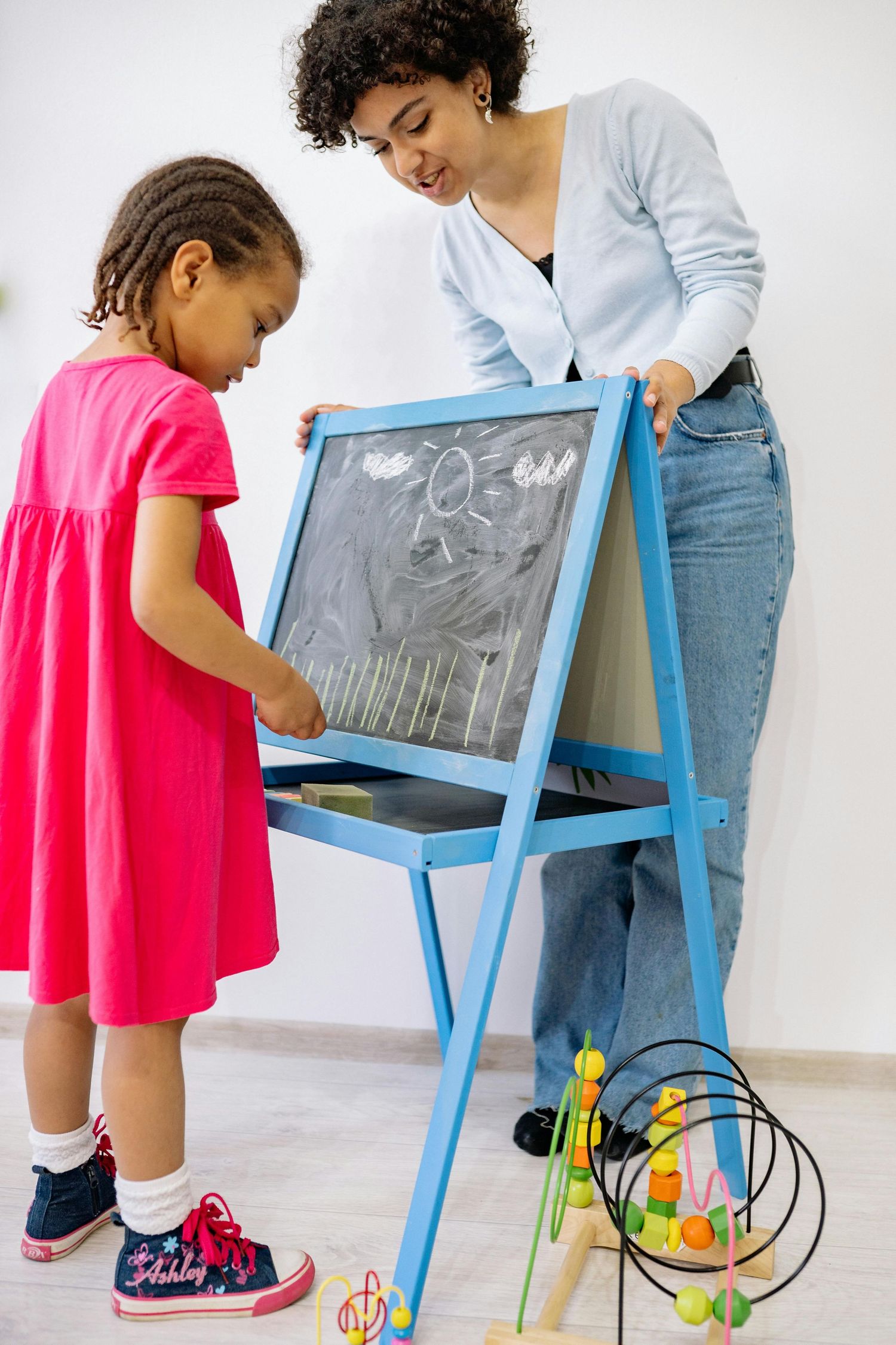 Queen Creek  Arizona Daycare Photography Students practice drawing and learning at a blue easel with educational toys.