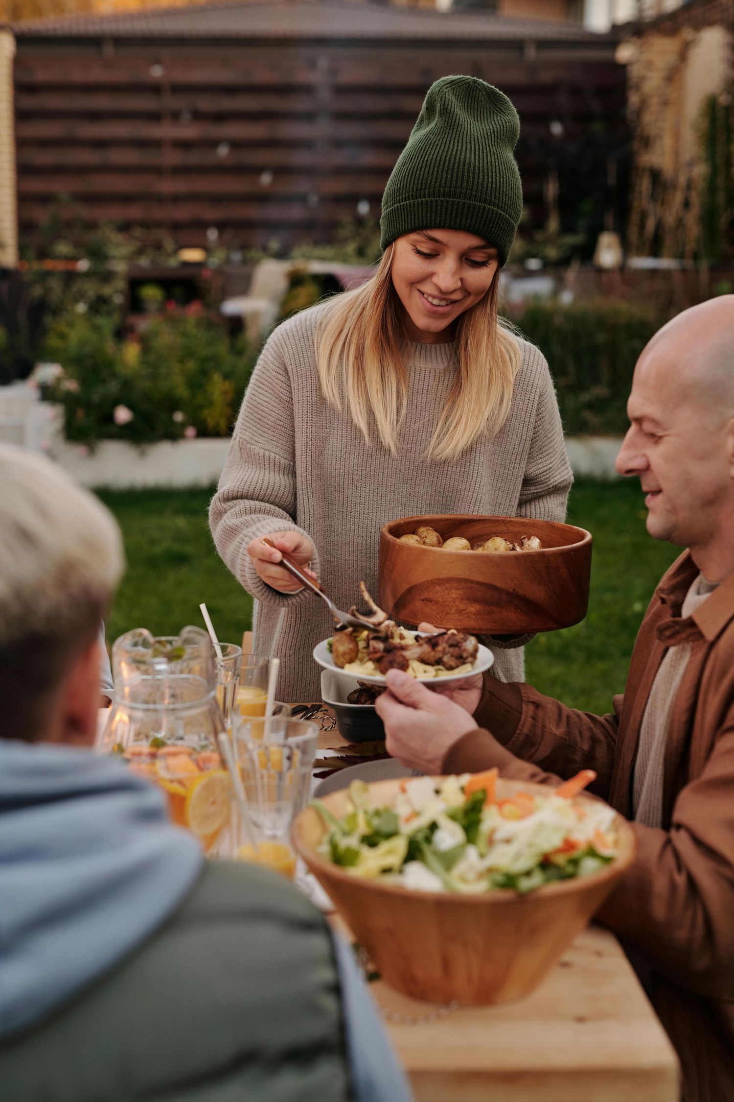 Family photography Arizona. People enjoying an outdoor dinner gathering with wooden bowls of fresh salads and food on a rustic table.