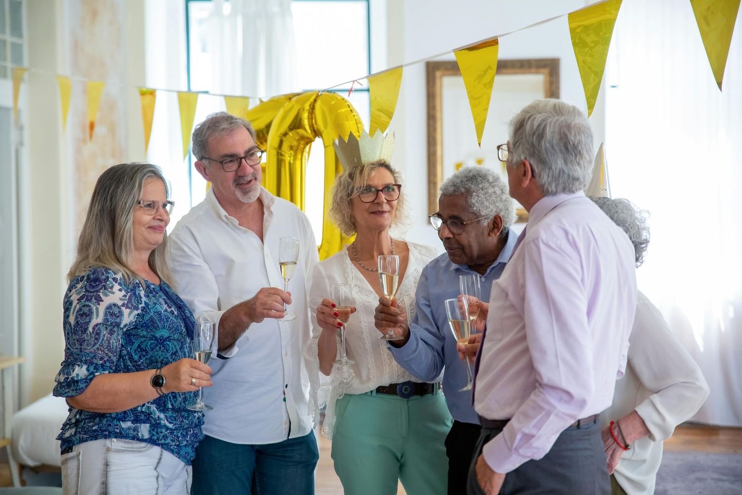 Luxury Photographer Paradise Valley. Group of people celebrating at a bright indoor gathering with yellow banner decorations.