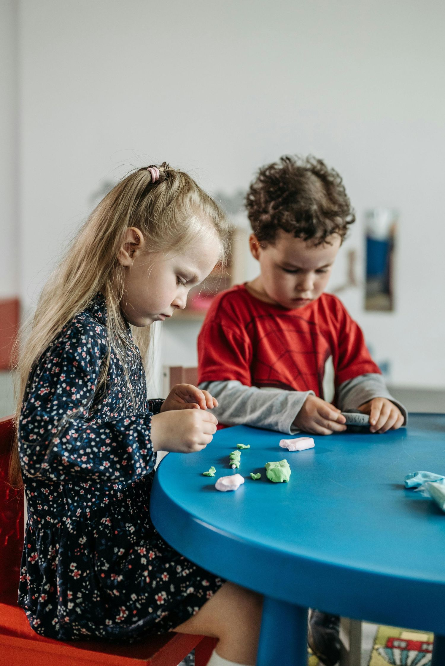 Scottsdale Arizona Photography Children focused on crafting activity at blue table in classroom setting.