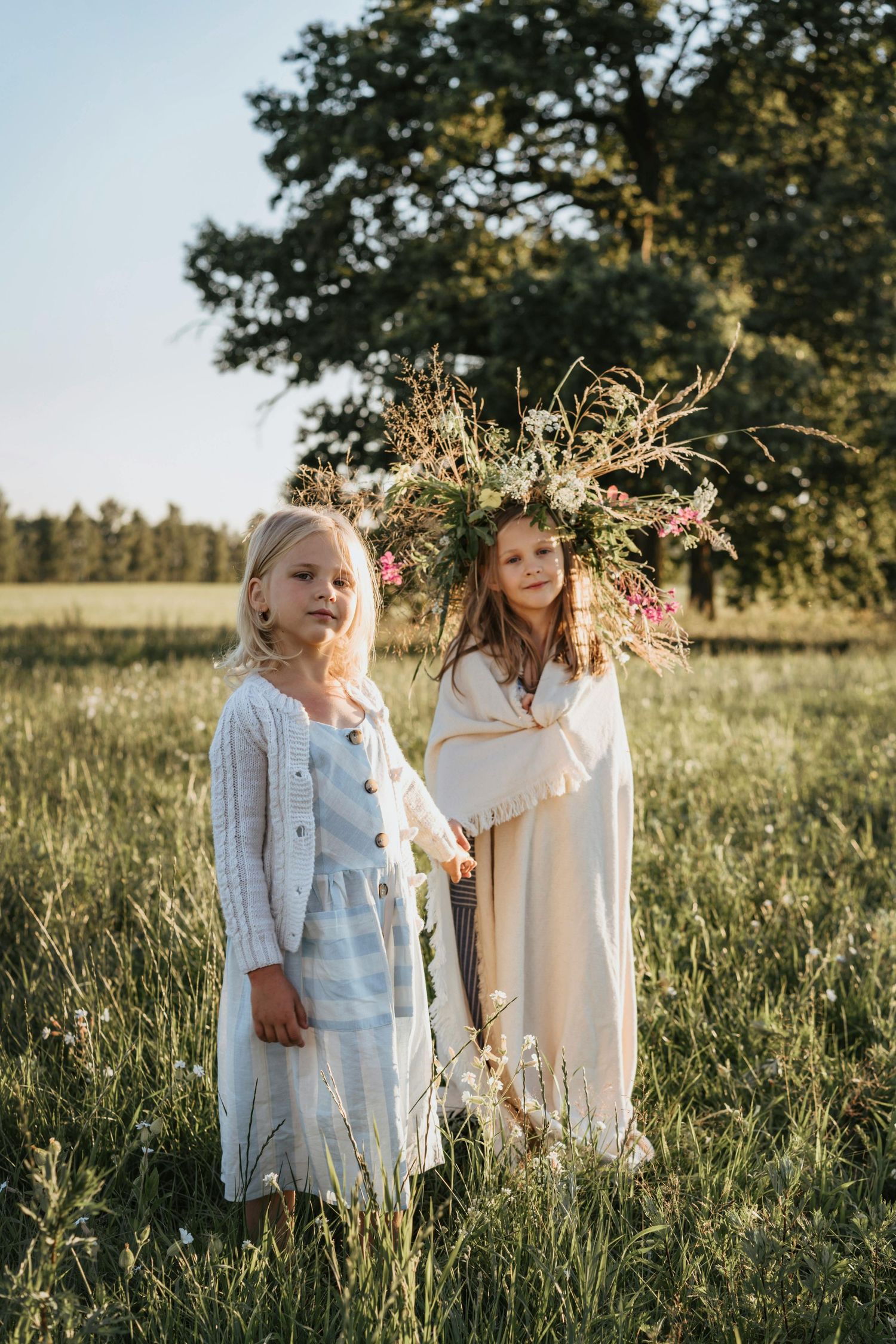 Children's outdoor photography Flagstaff Arizona wearing light summer clothing stand together in a golden-lit field with wildflowers.