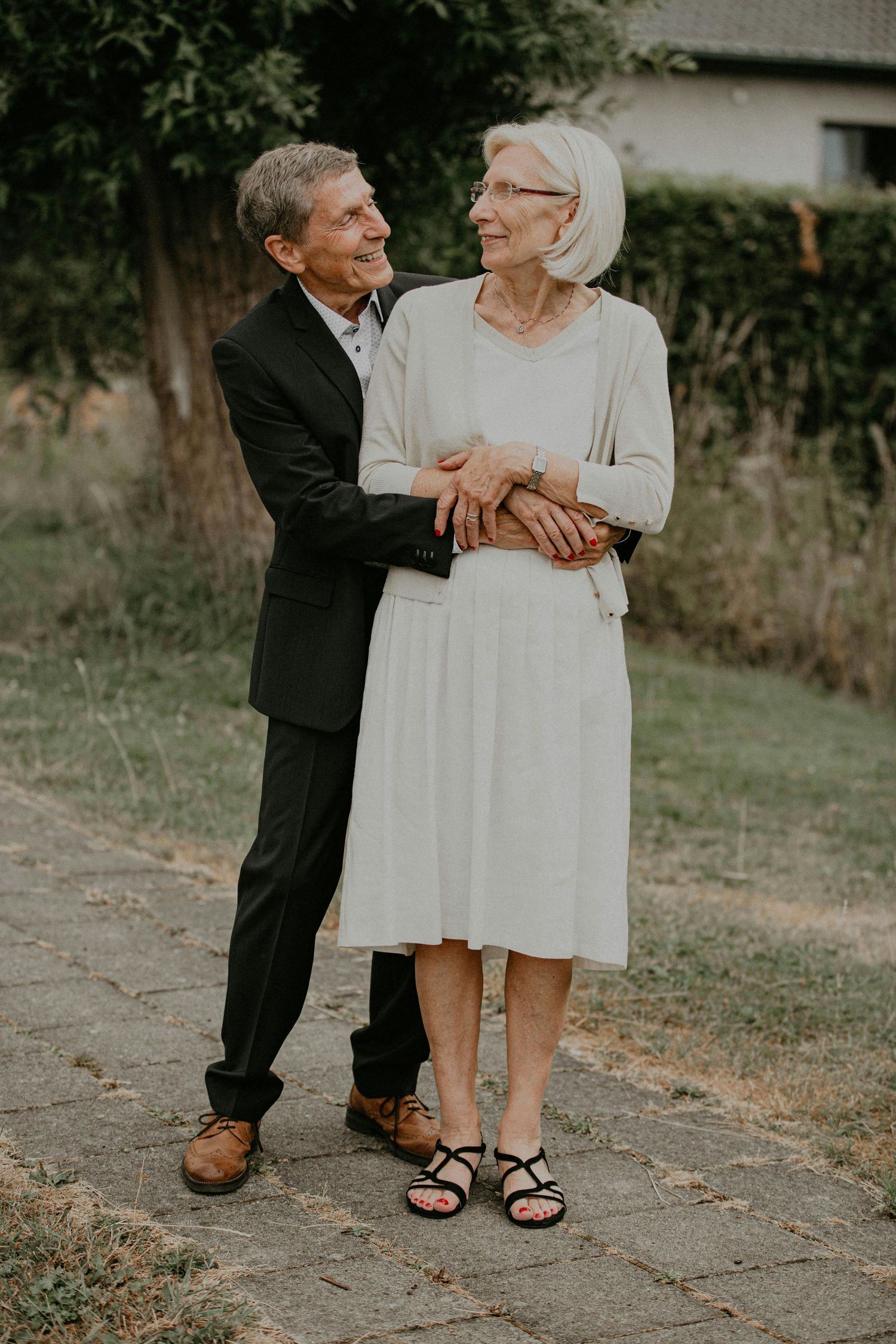 Close-up view of feet and legs showing contrasting formal and casual footwear on a gravel path.