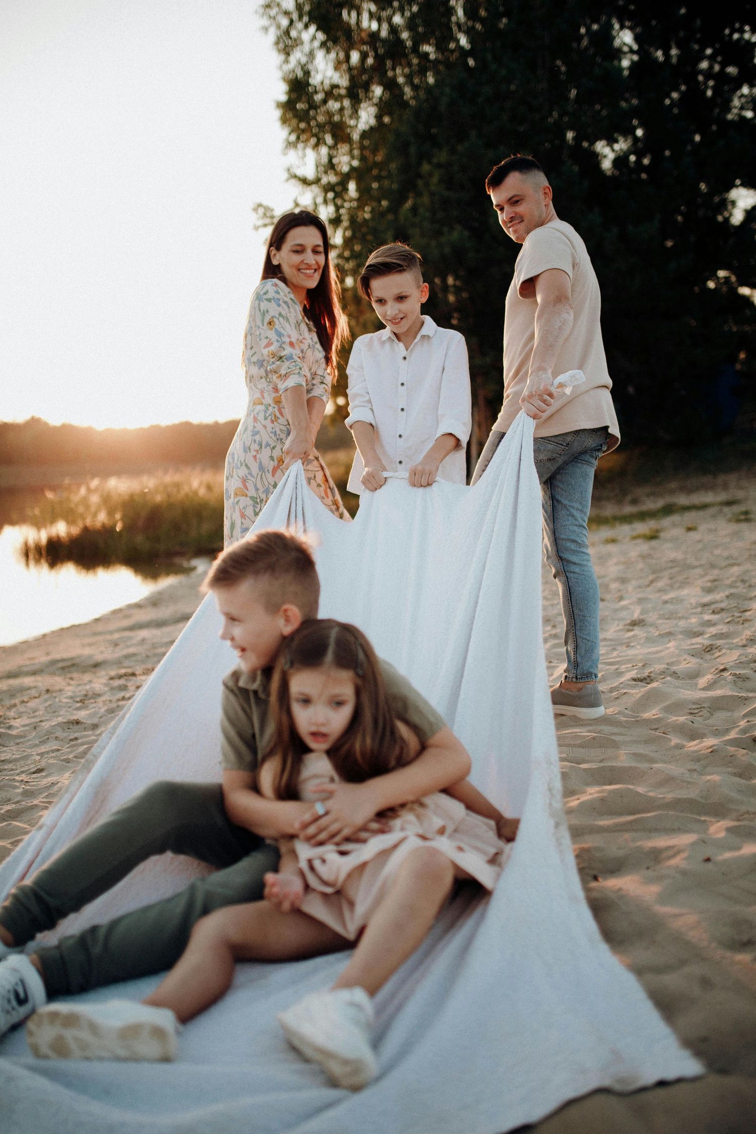 Prescott Arizona, mountaintop Family photography, Candid moments of a family relaxing on a white blanket at the beach during sunset.