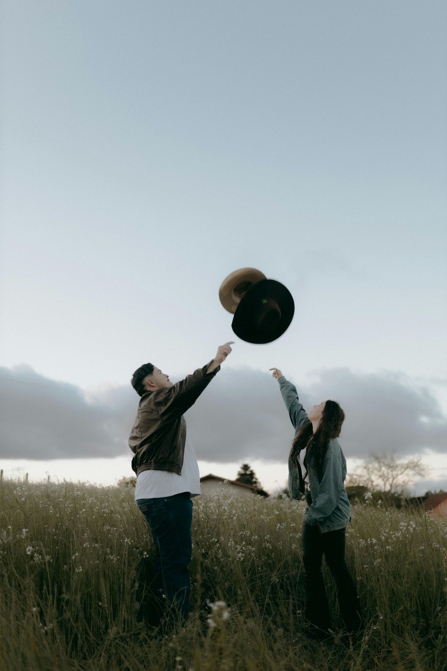 Two people dance together in a grassy meadow at dusk, creating a playful silhouette against the moody sky. Top Photographer Scottsdale.